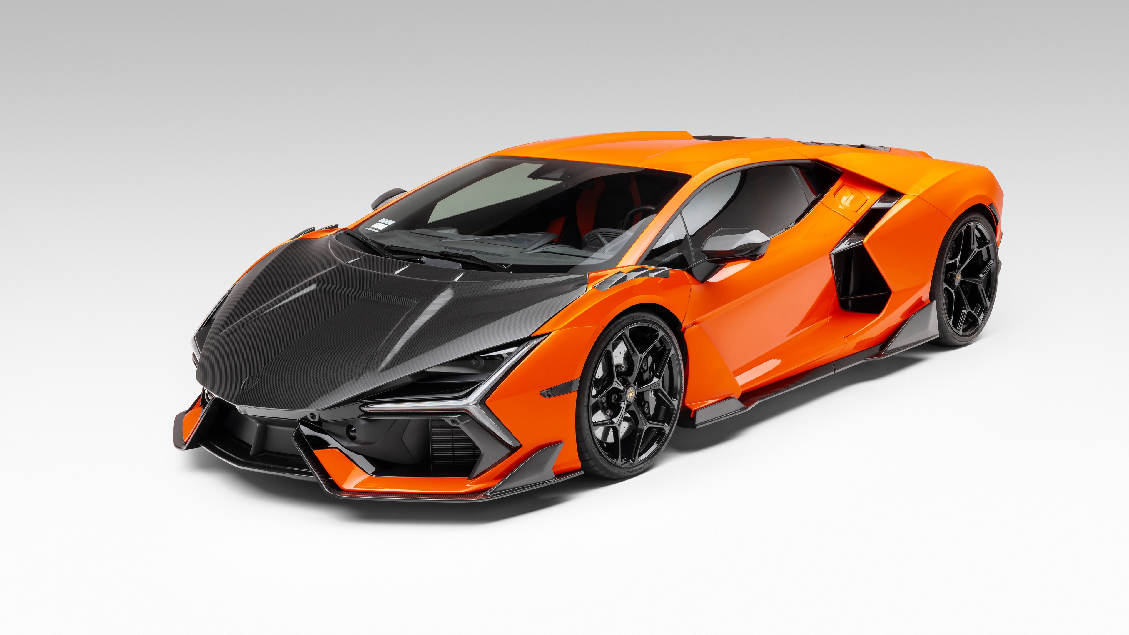 A high-detail close-up of a Lamborghini Revuelto featuring premium carbon fiber accents on a clean white background.