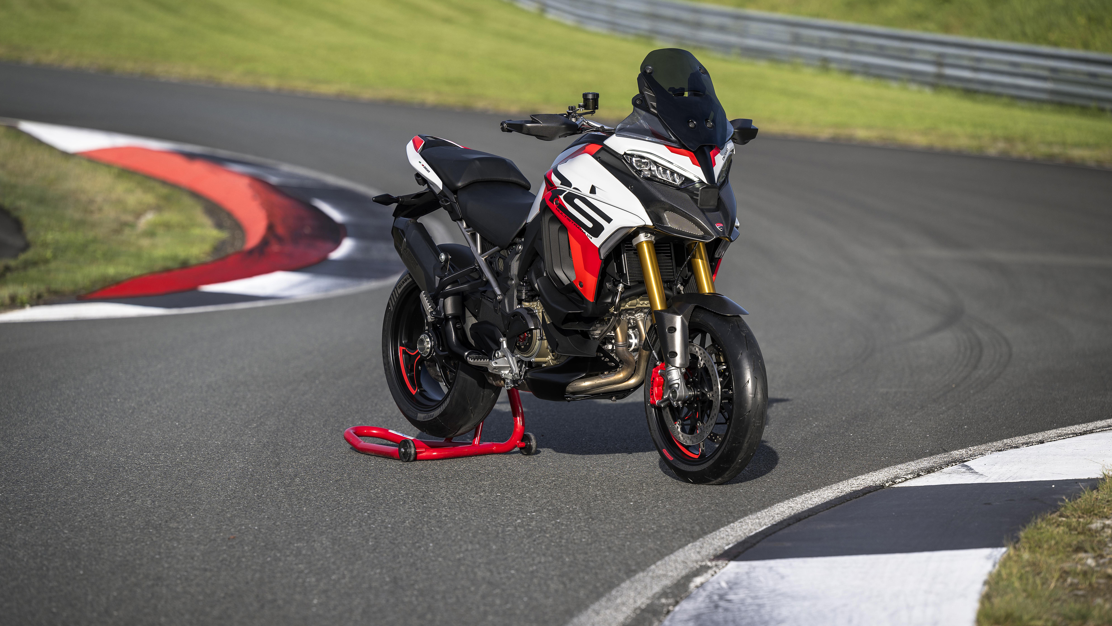 A 2024 Ducati Multistrada V4 RS adventure motorcycle speeding along a professional race track curve.