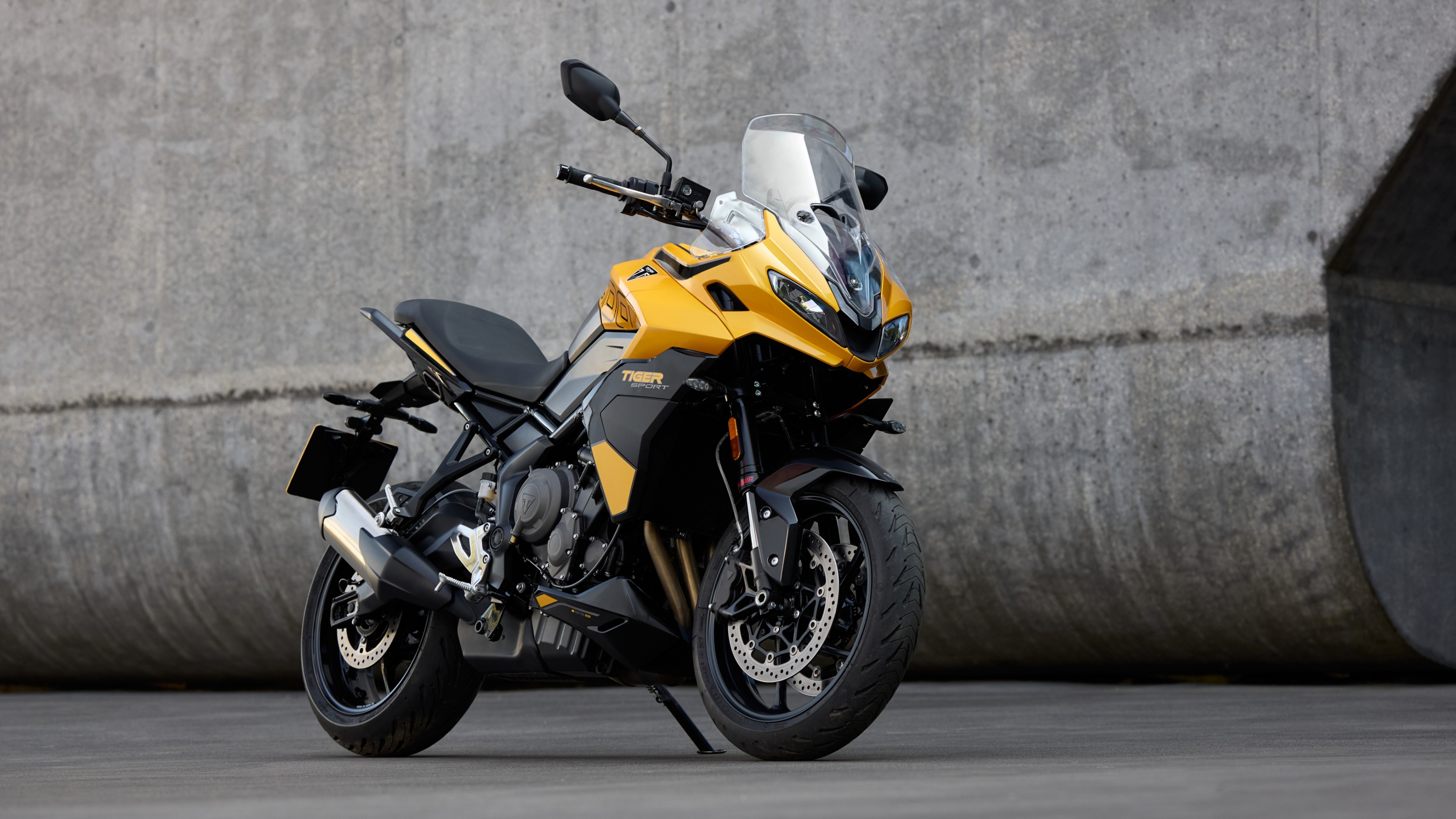 A sleek and modern 2025 adventure motorcycle riding through a mountainous, rocky landscape.