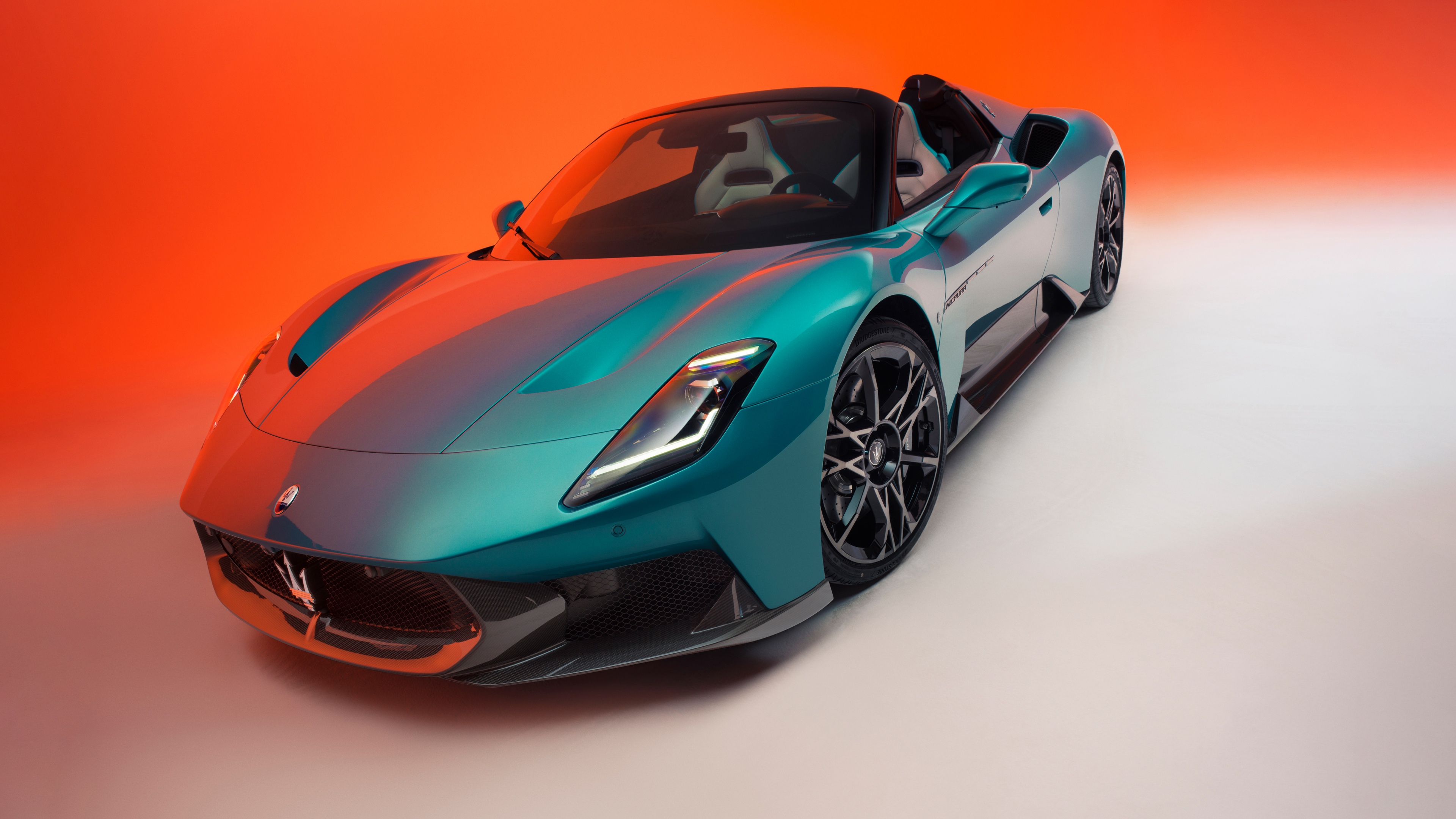 A sleek Maserati MCPURA Cielo supercar with aerodynamic contours set against a colorful gradient background.