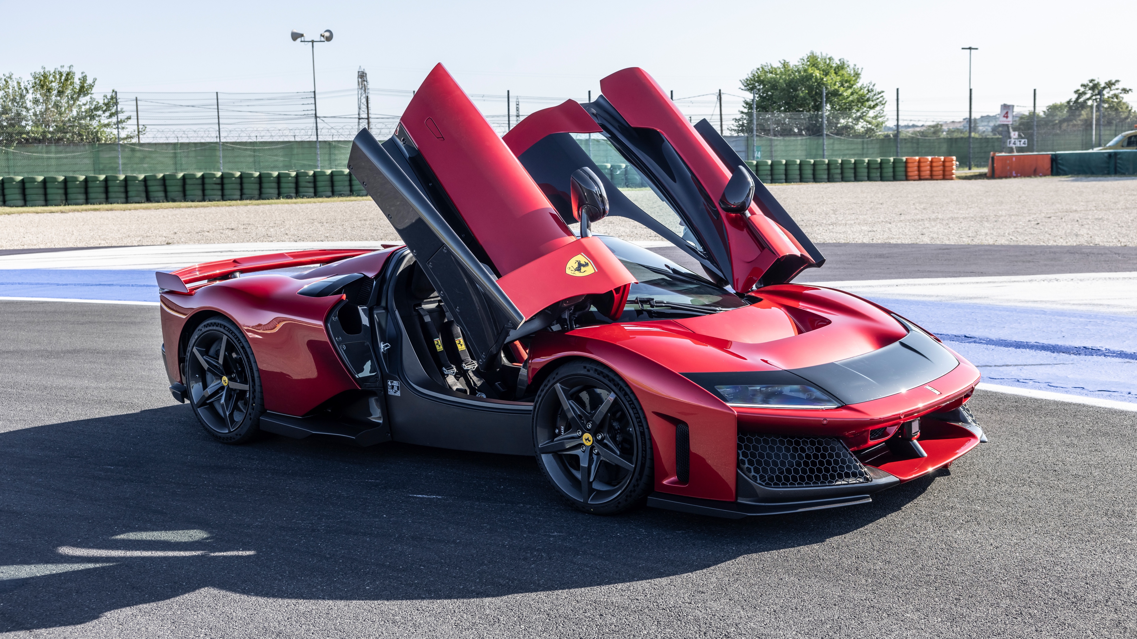 A high-performance red Ferrari F80 hypercar speeding along a professional race track.