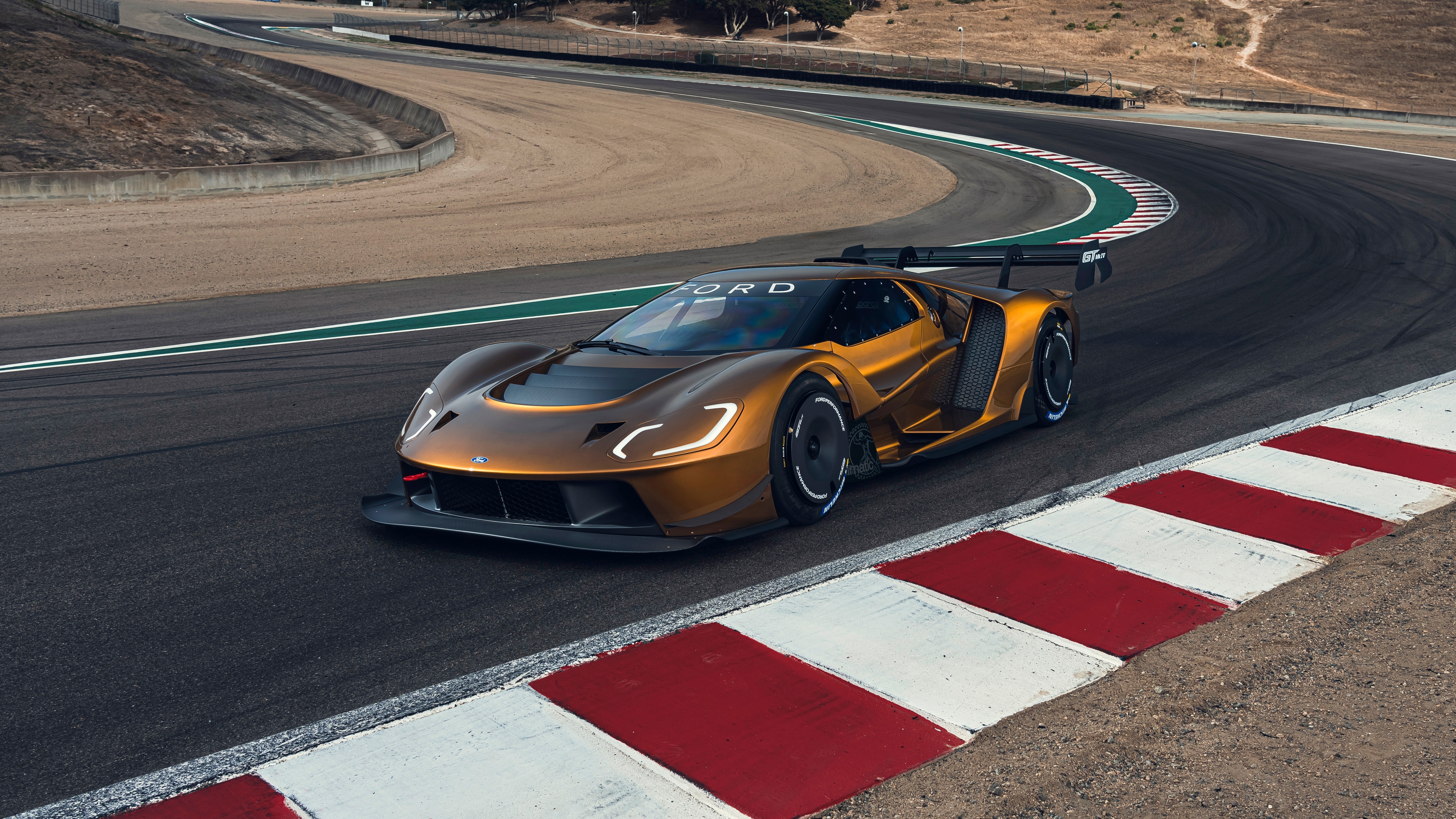 A high-performance Ford GT Mk IV supercar driving at high speed on a professional racing circuit.