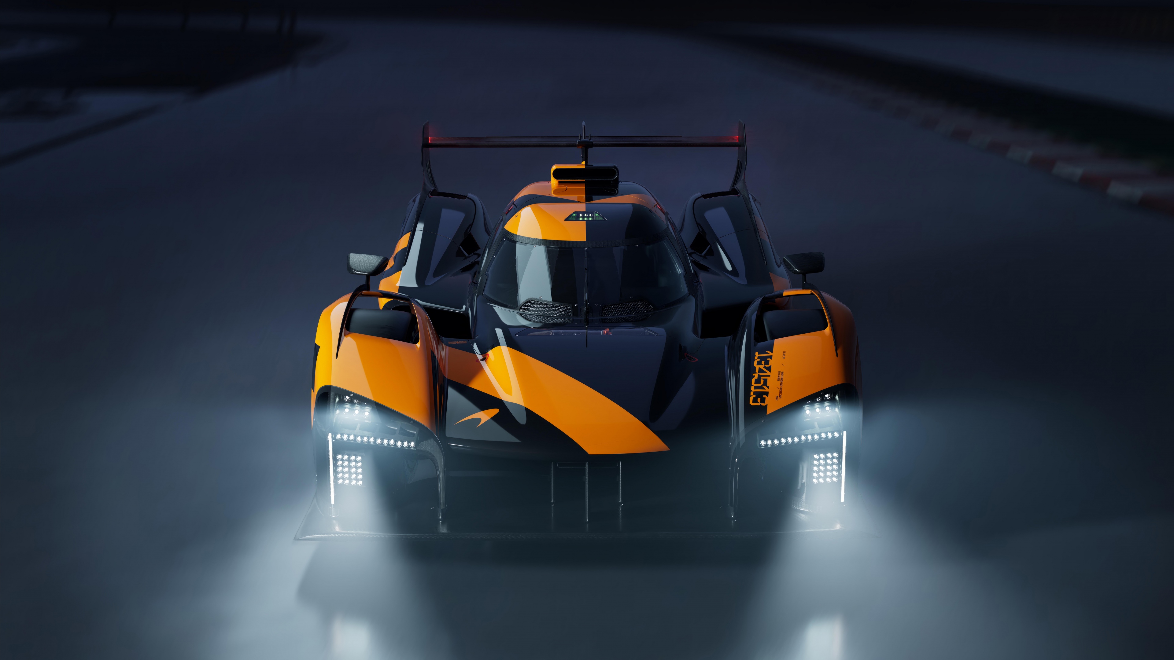 A vibrant orange McLaren Project Endurance Le Mans Hypercar captured during a night race on a professional track.