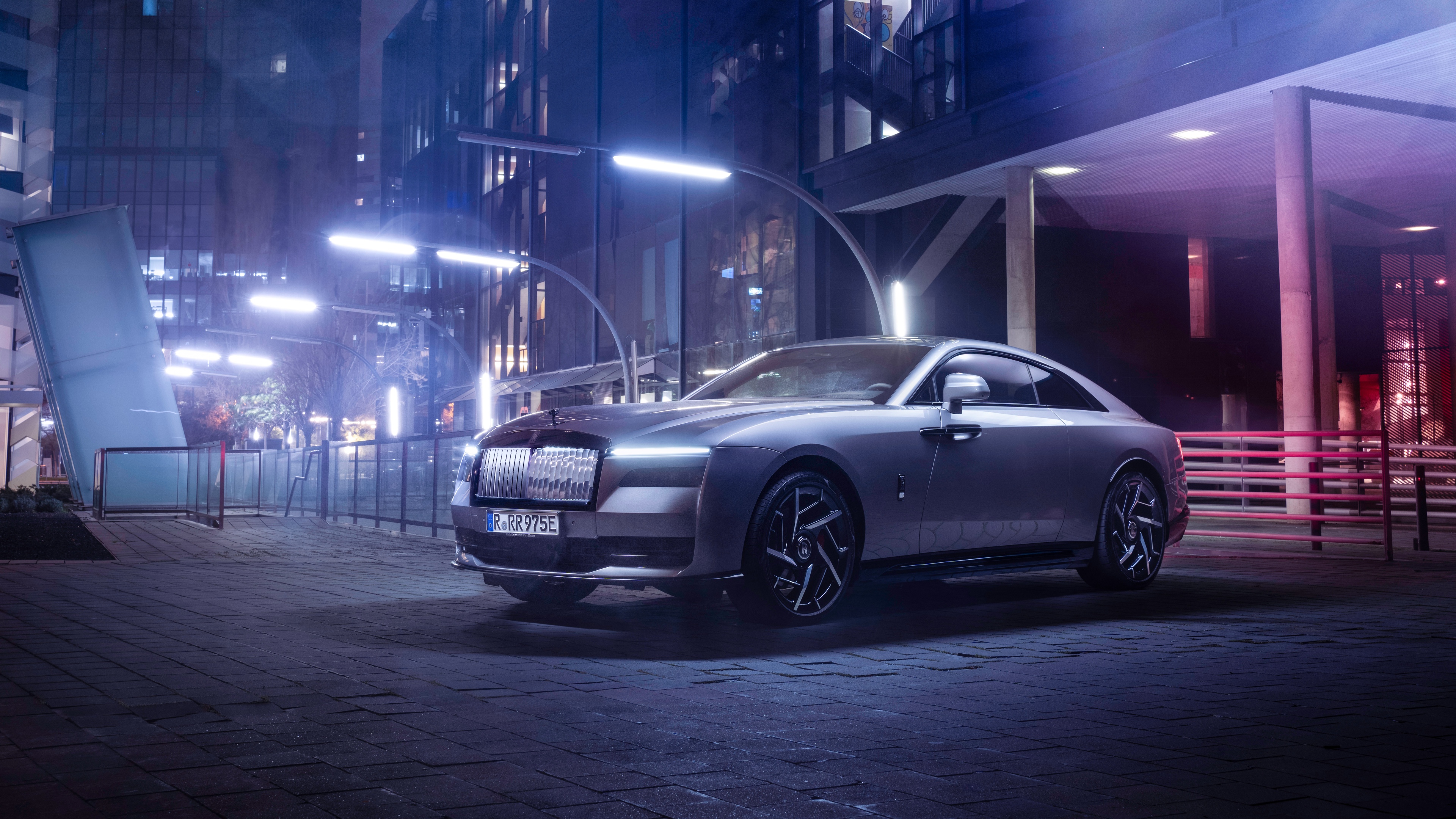 Rolls-Royce Black Badge Spectre luxury car with vibrant neon light reflections at night.