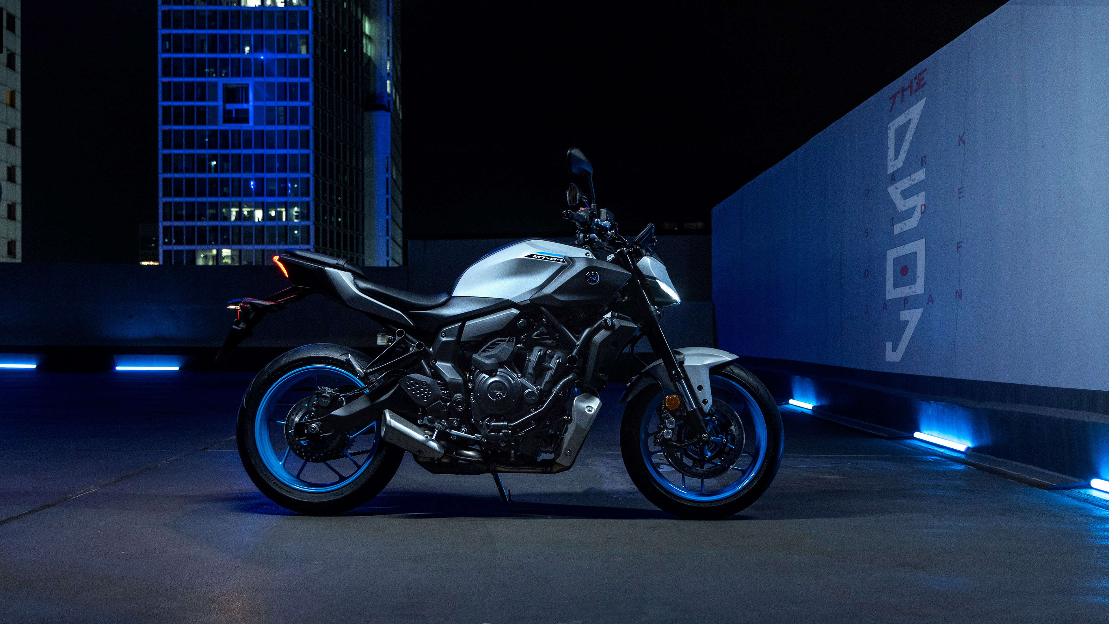 A sleek 2025 Yamaha MT-07 motorcycle parked in a dark, atmospheric night setting with urban lighting.