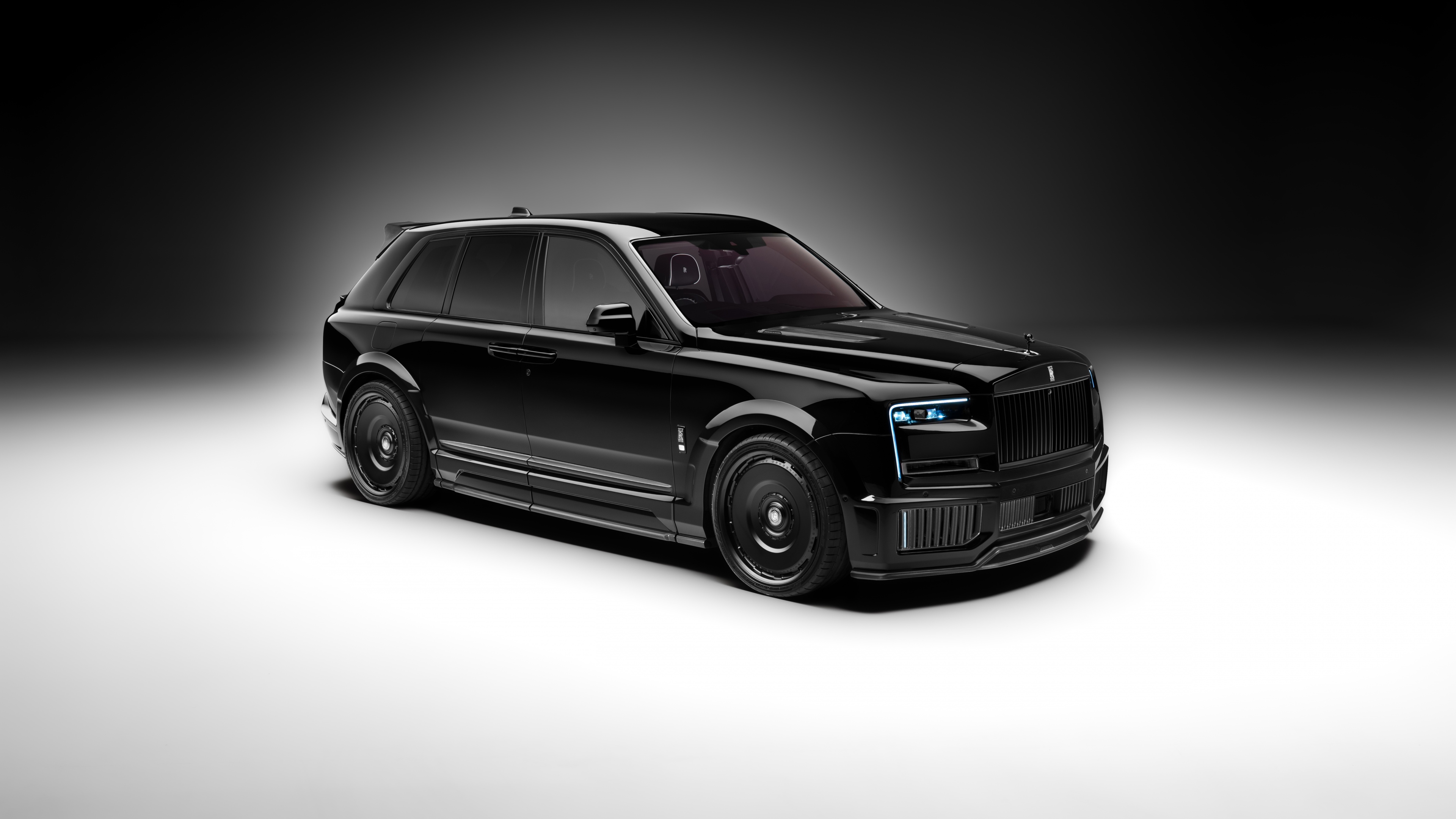 A collection of polished black luxury cars positioned against a dark, moody background with dramatic lighting.