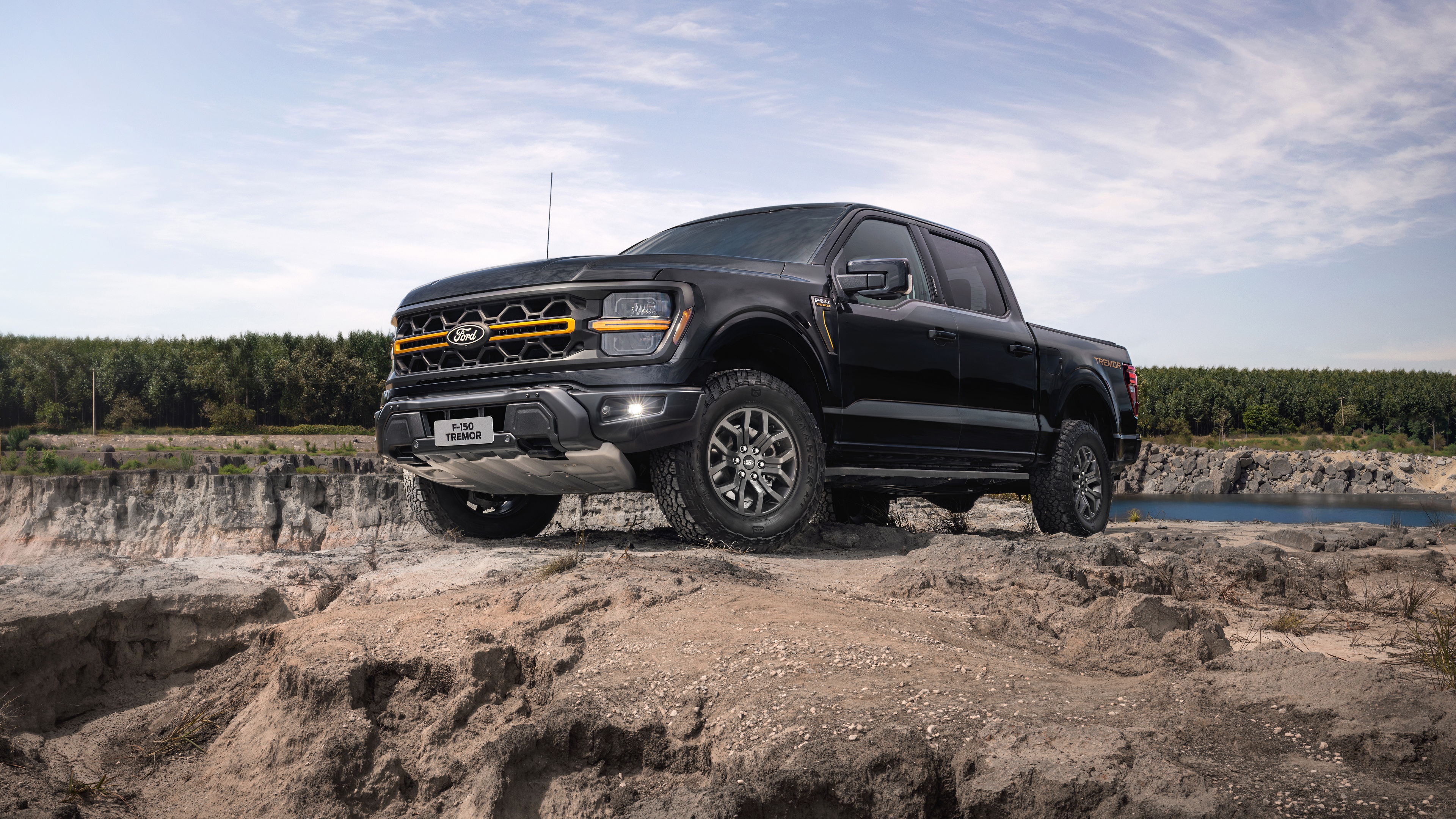 A fleet of modern, high-detail off-road trucks traversing a dusty, rocky desert landscape.