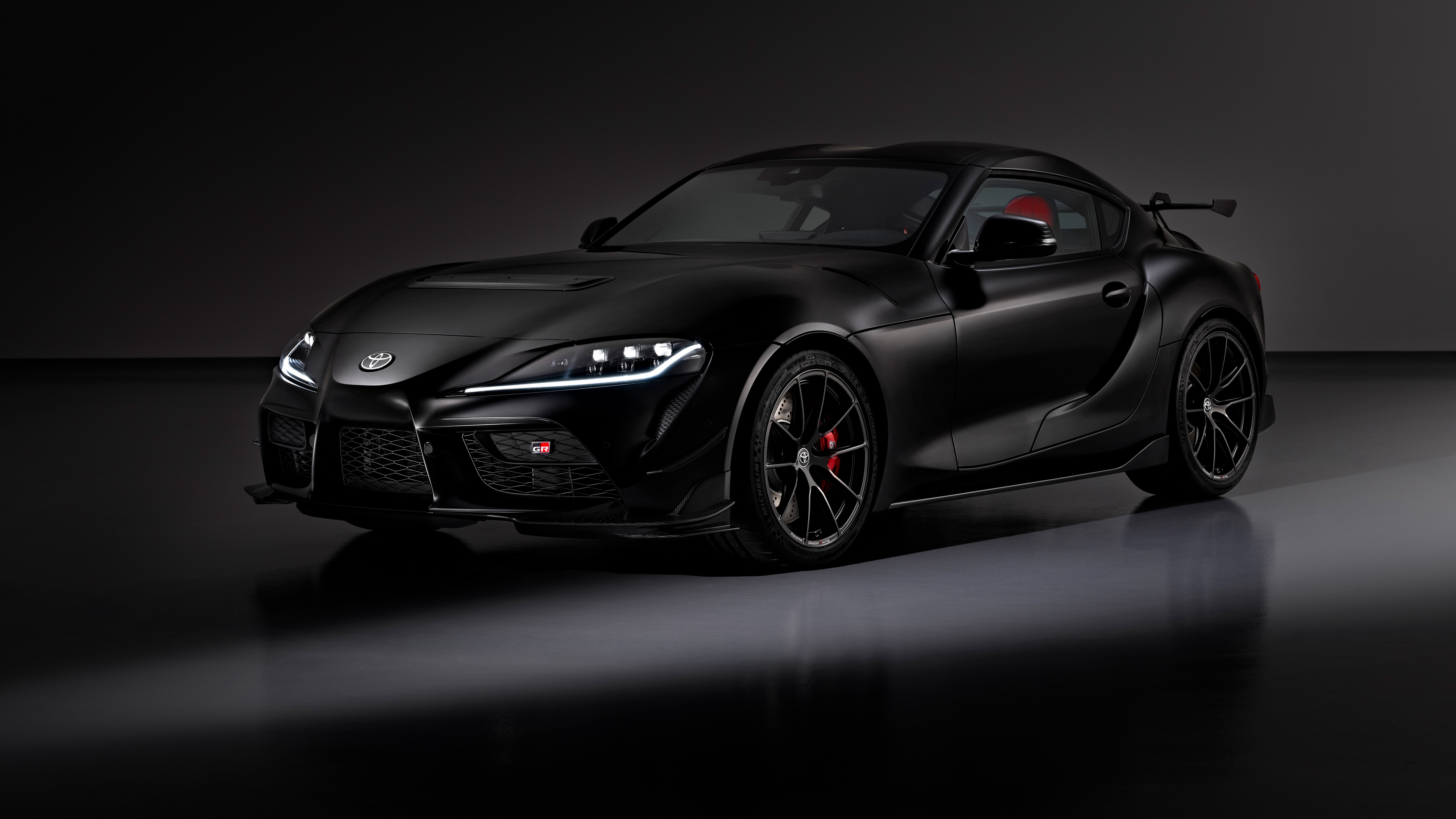 A sleek, black 2025 Toyota GR Supra A90 Final Edition presented in a dark, atmospheric studio setting.