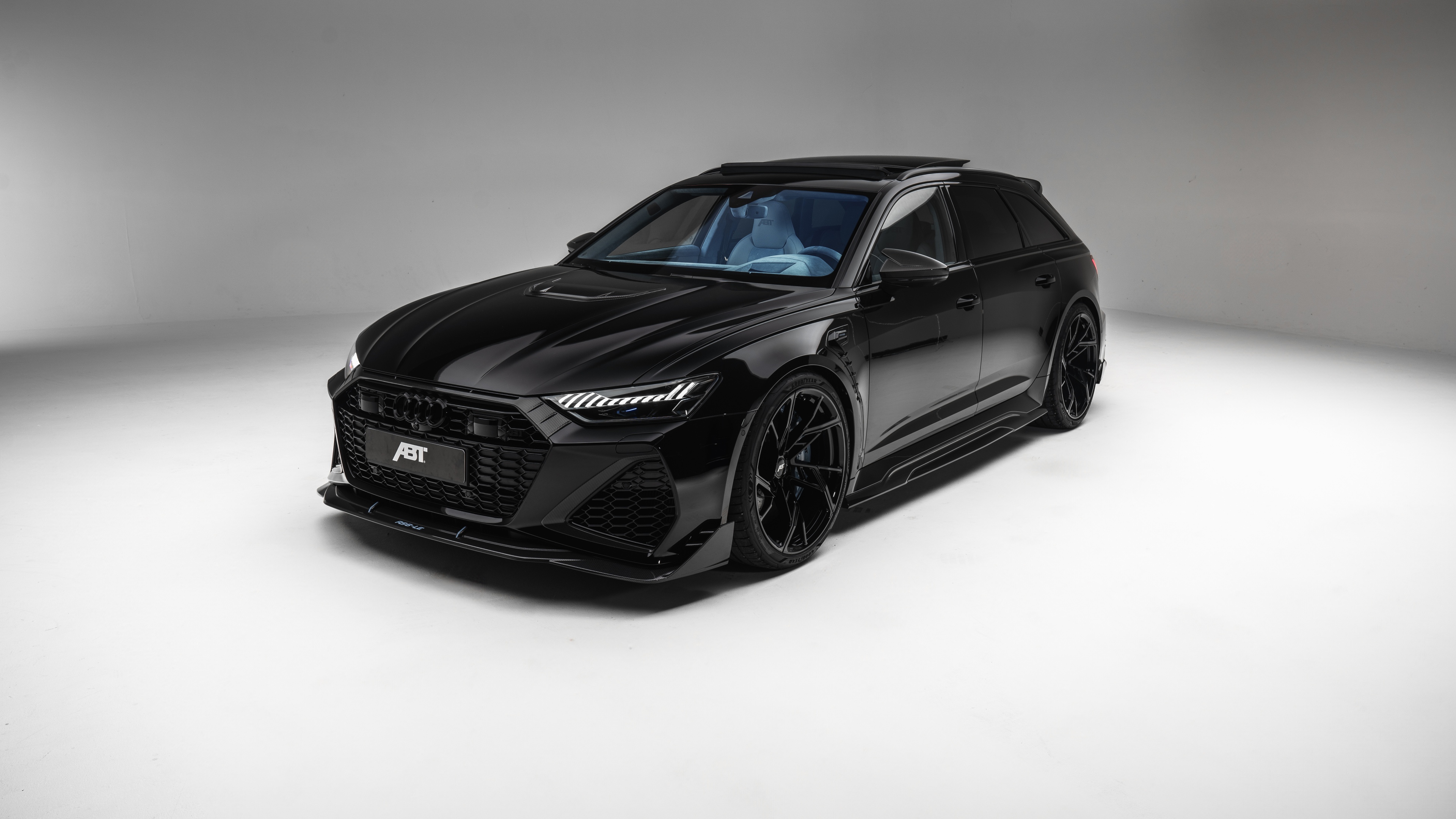 A collection of glossy black luxury cars with sleek aerodynamic designs in a high-tech futuristic setting.