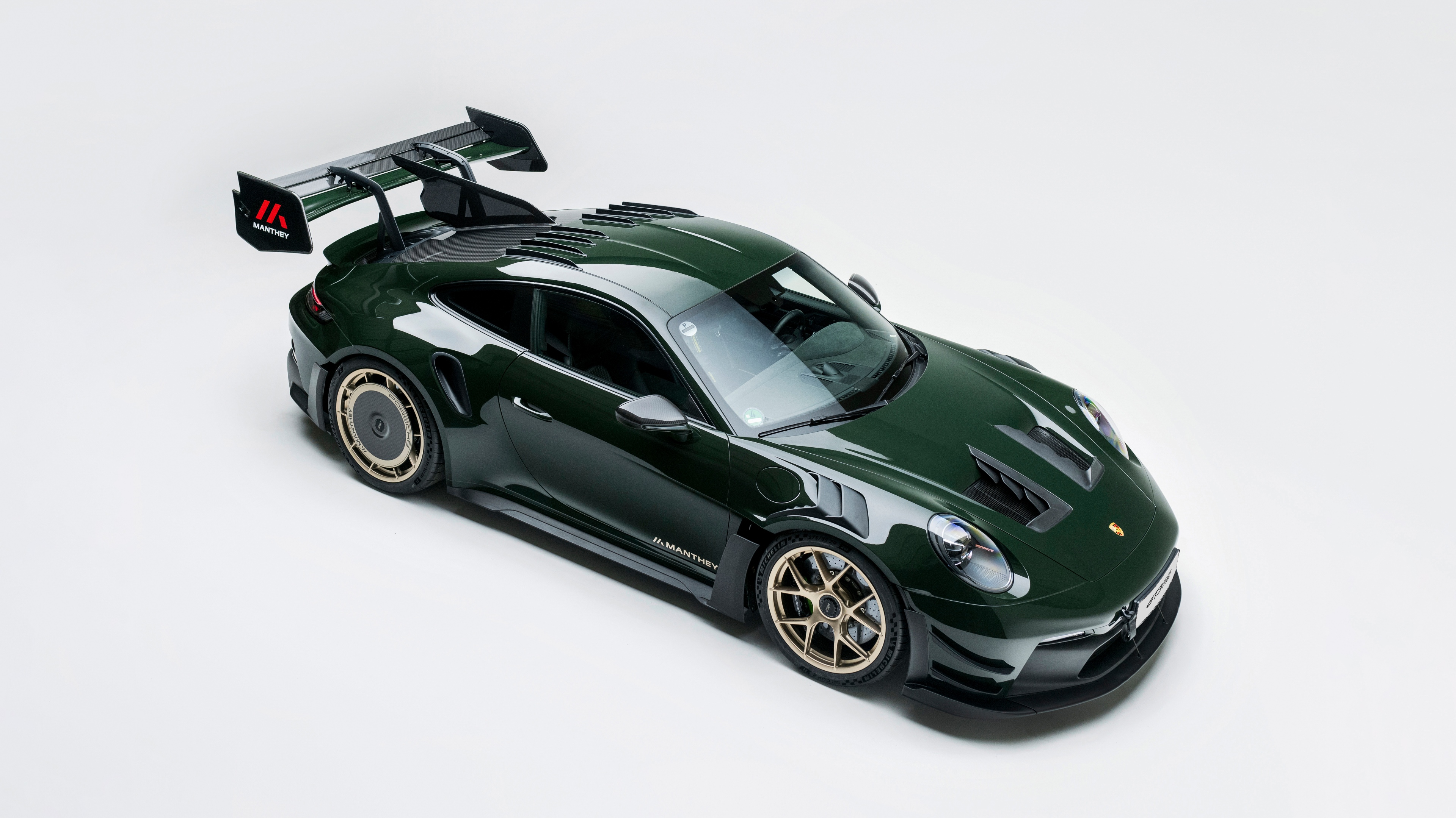 A high-detail studio shot of a Porsche 911 GT3 RS equipped with a Manthey Performance Kit on a seamless white background.