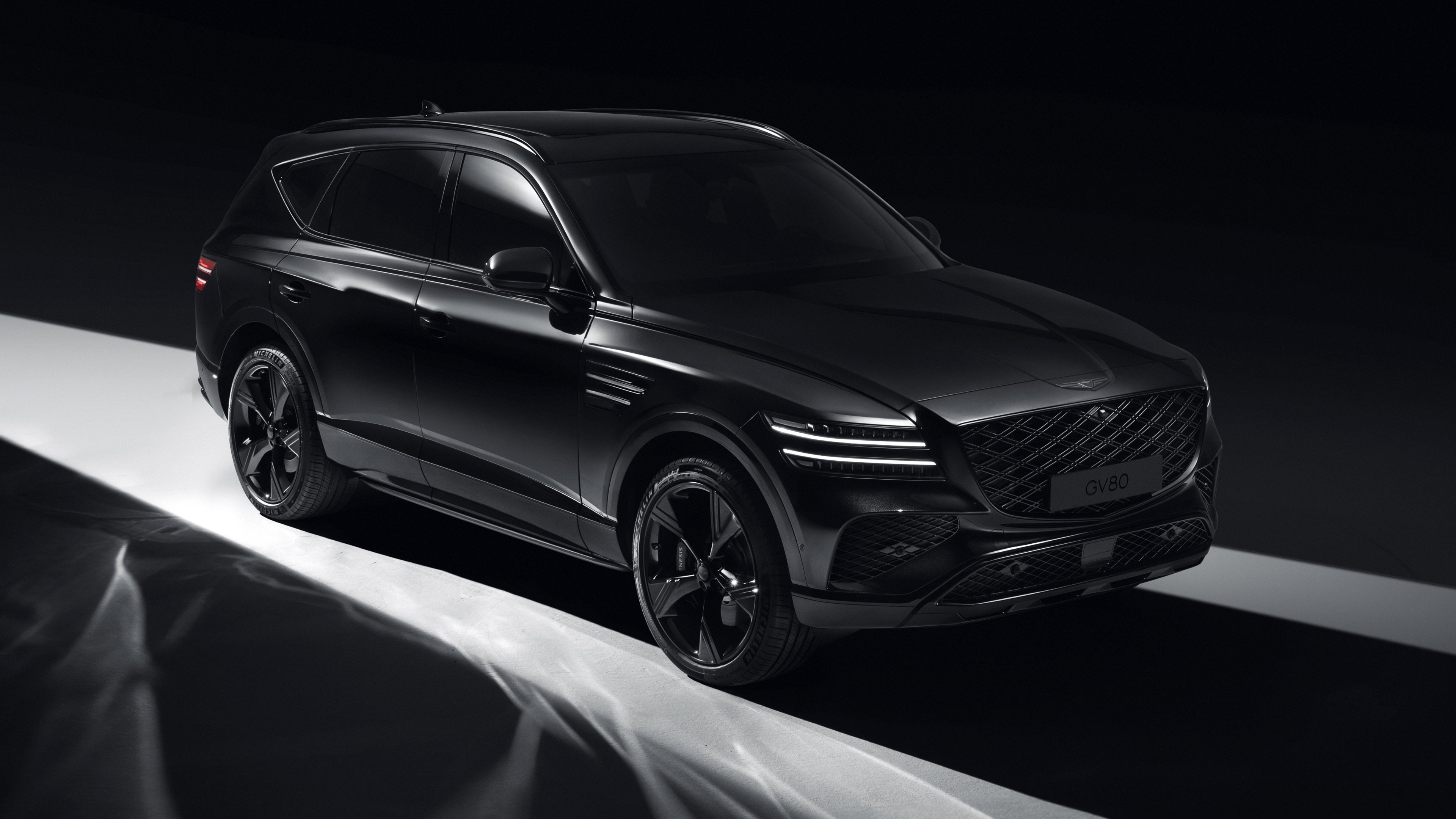A high-resolution shot of a black electric SUV in a dark, minimalist setting.