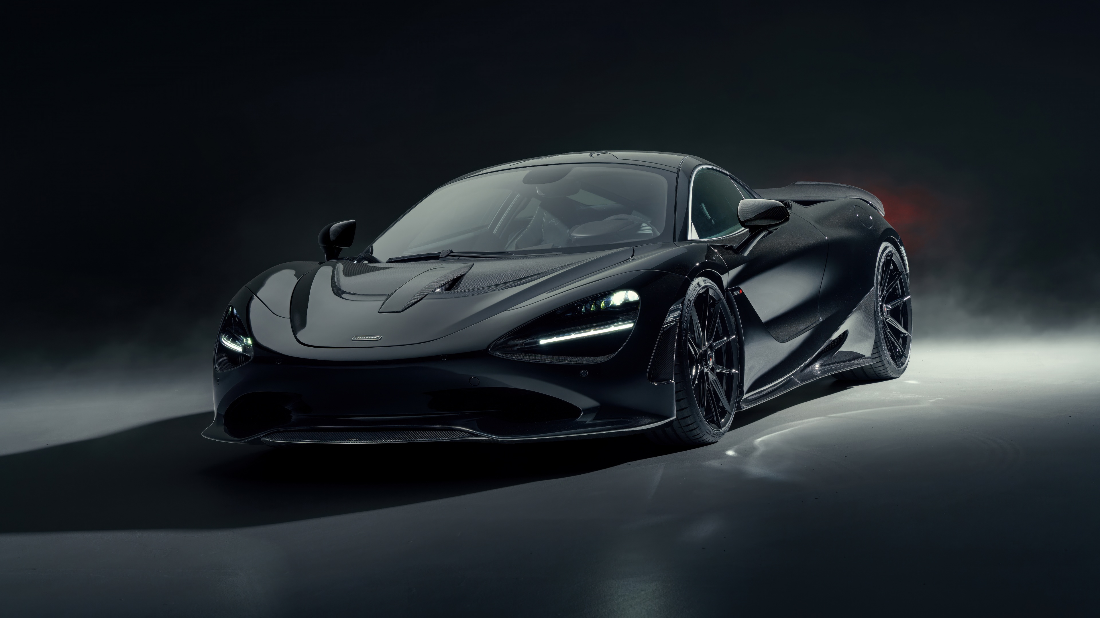 High-performance black cars positioned in a dark, atmospheric setting with dramatic shadows and metallic reflections.