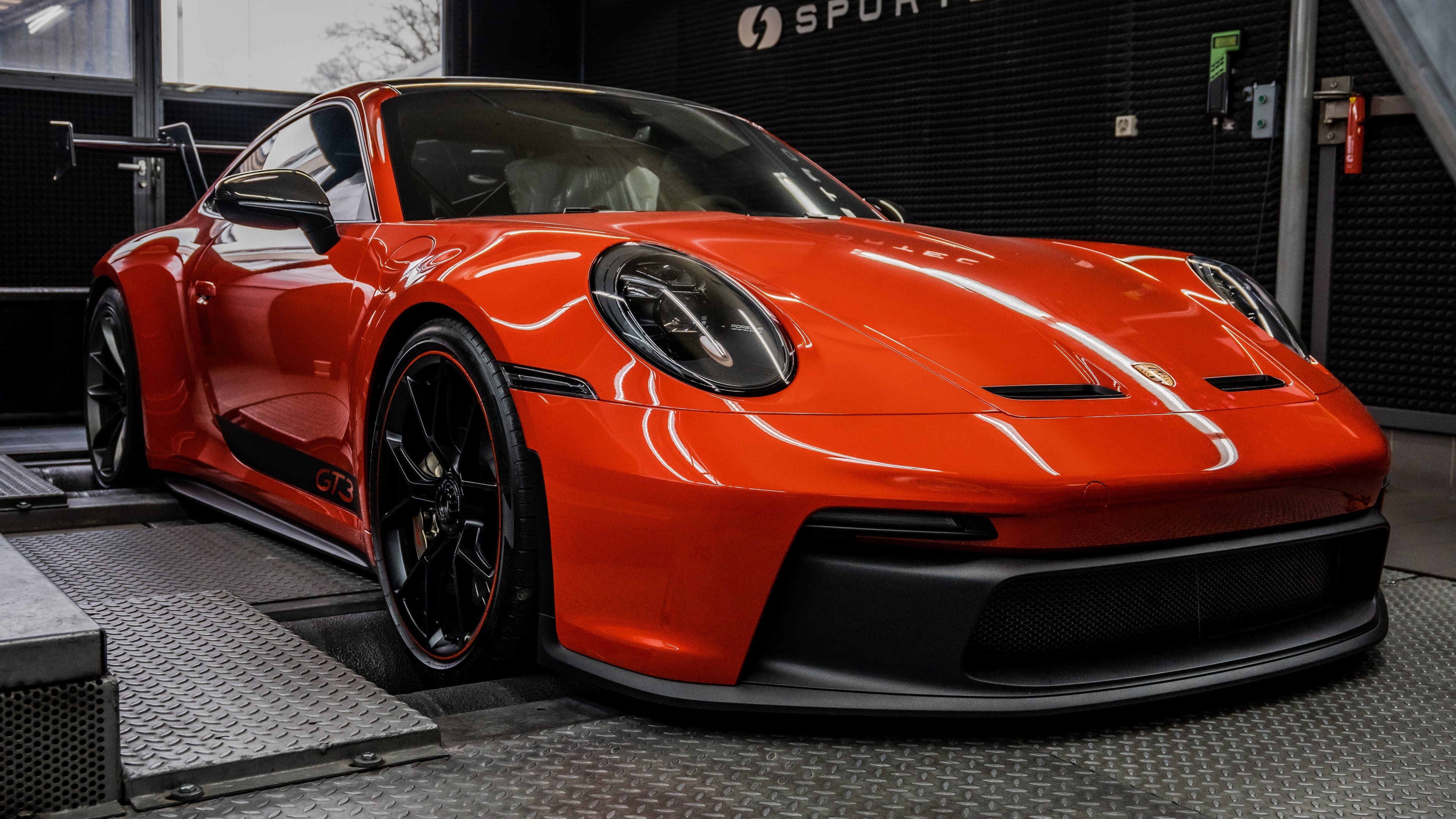 A high-resolution, detailed shot of a bright orange Porsche 911 GT3 Clubsport racing car.