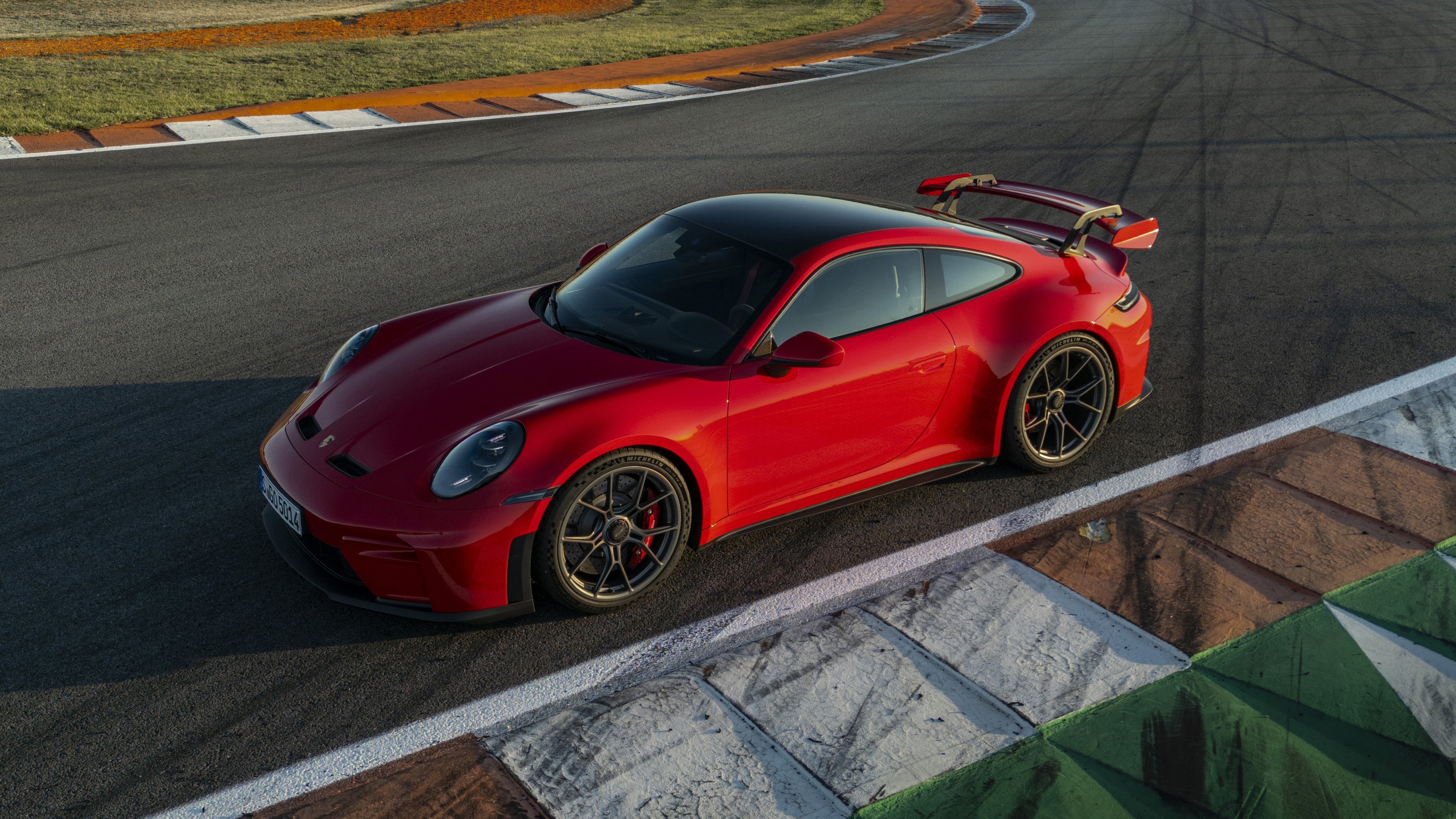 A vibrant red Porsche 911 GT3 speeding along a paved racing circuit.