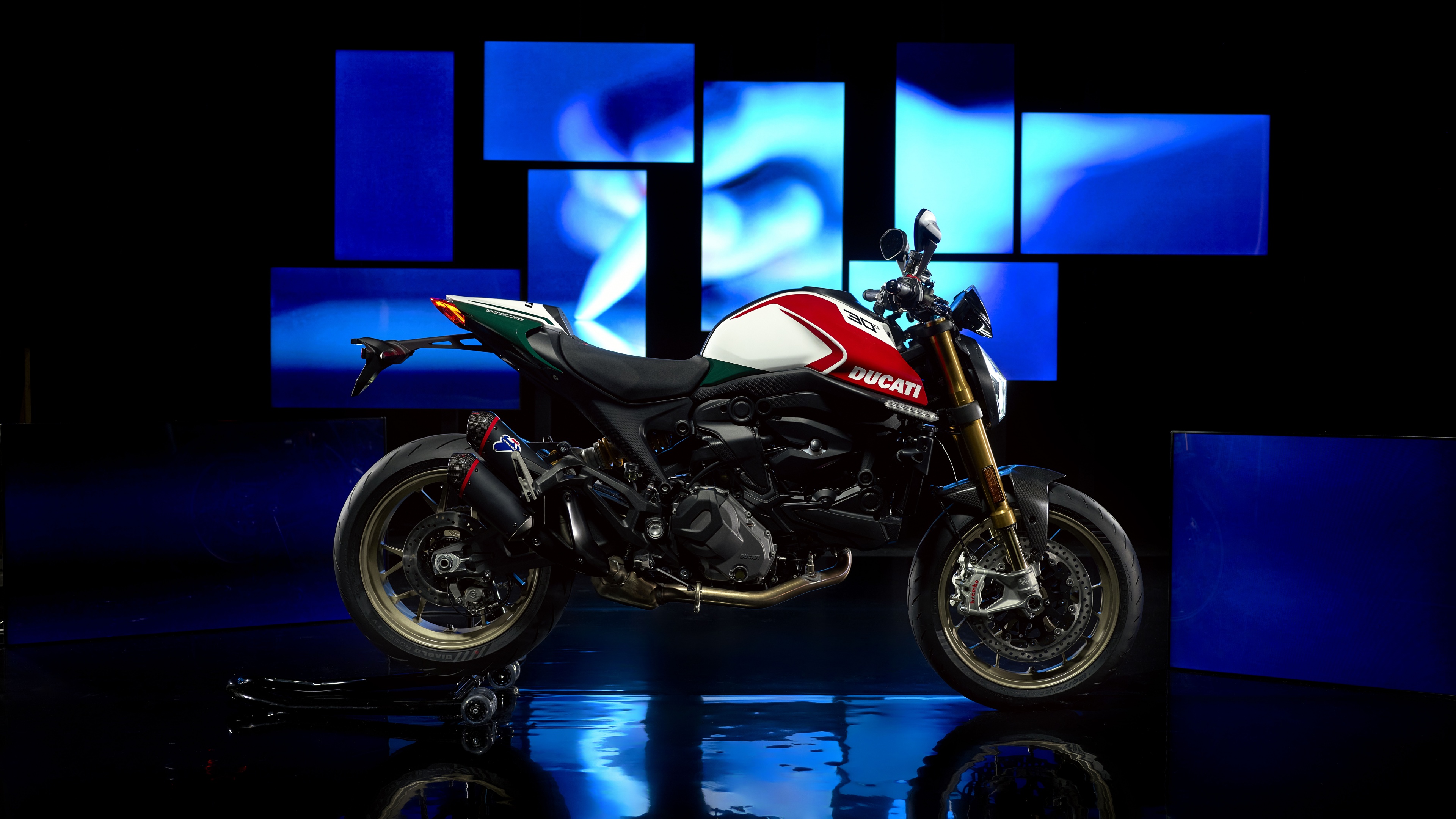 A cinematic, high-detail close-up of the 2024 Ducati Monster Anniversary Edition motorcycle against a dark, moody background.