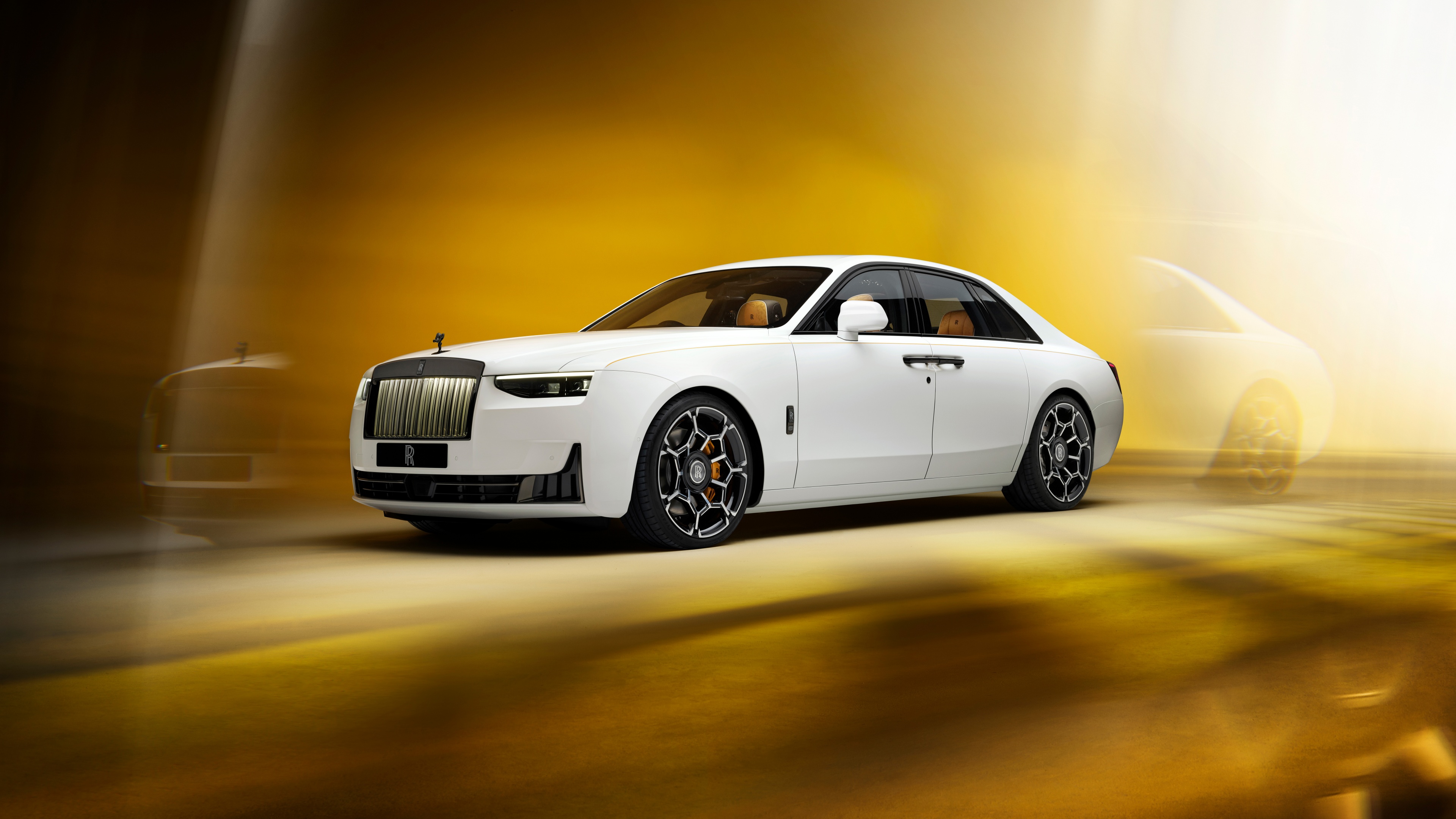 A sleek 2024 Rolls-Royce Black Badge Ghost Series II positioned against a radiant golden background.
