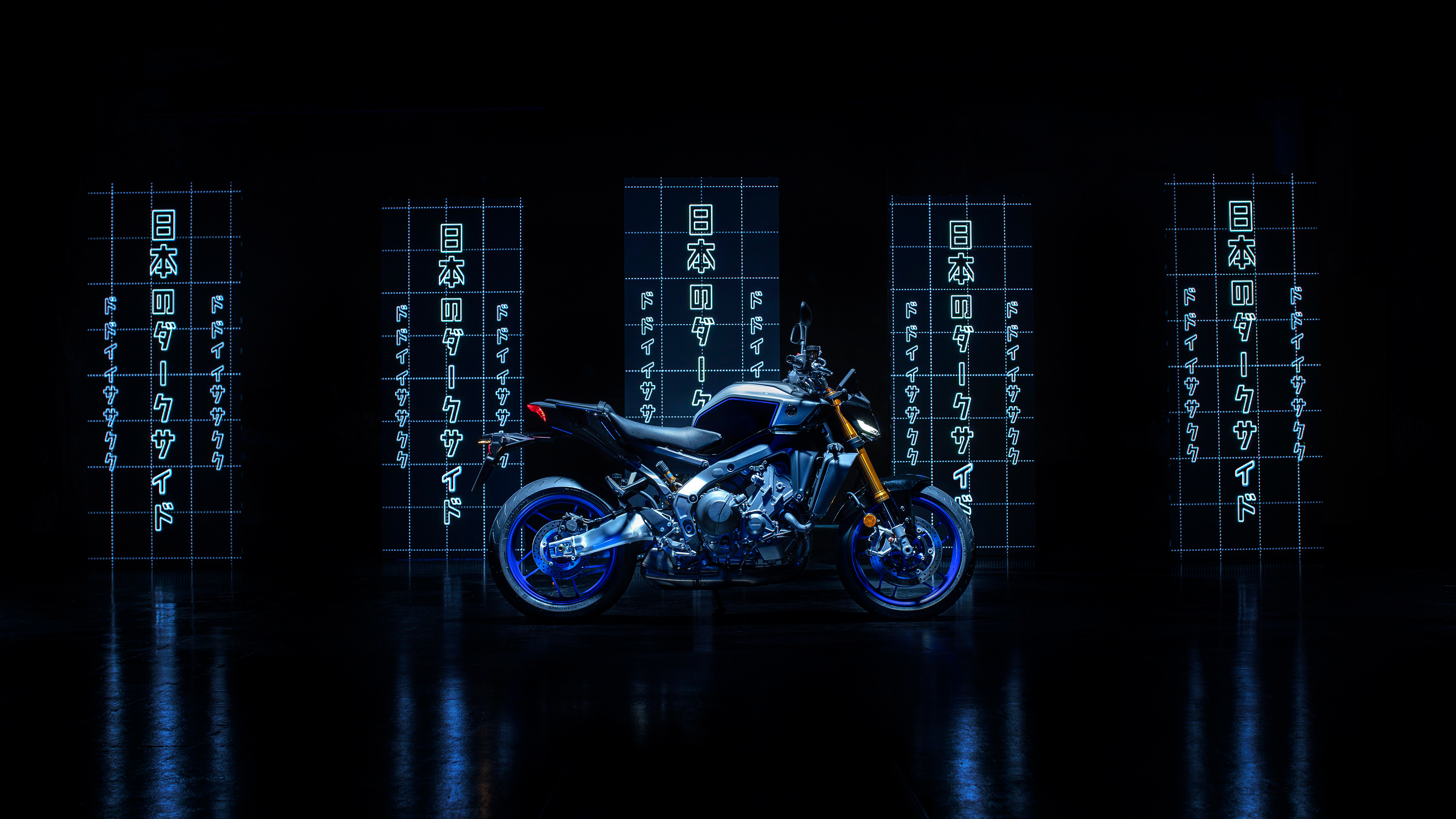A sleek 2024 Yamaha MT-09 motorcycle with vibrant lighting details against a pitch-black background.