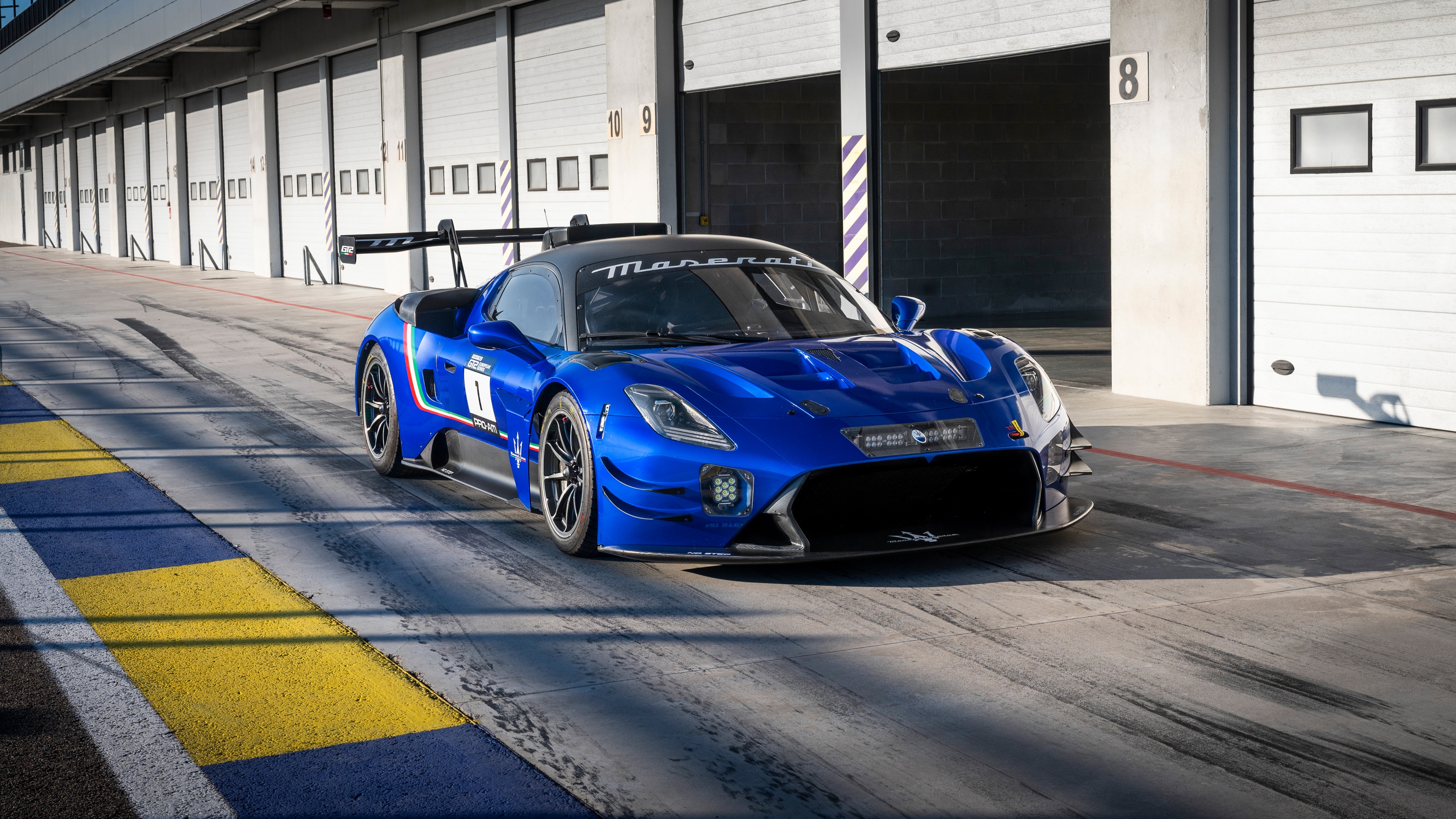 A 2025 Maserati GT2 race car speeding through a corner on a professional asphalt race track.