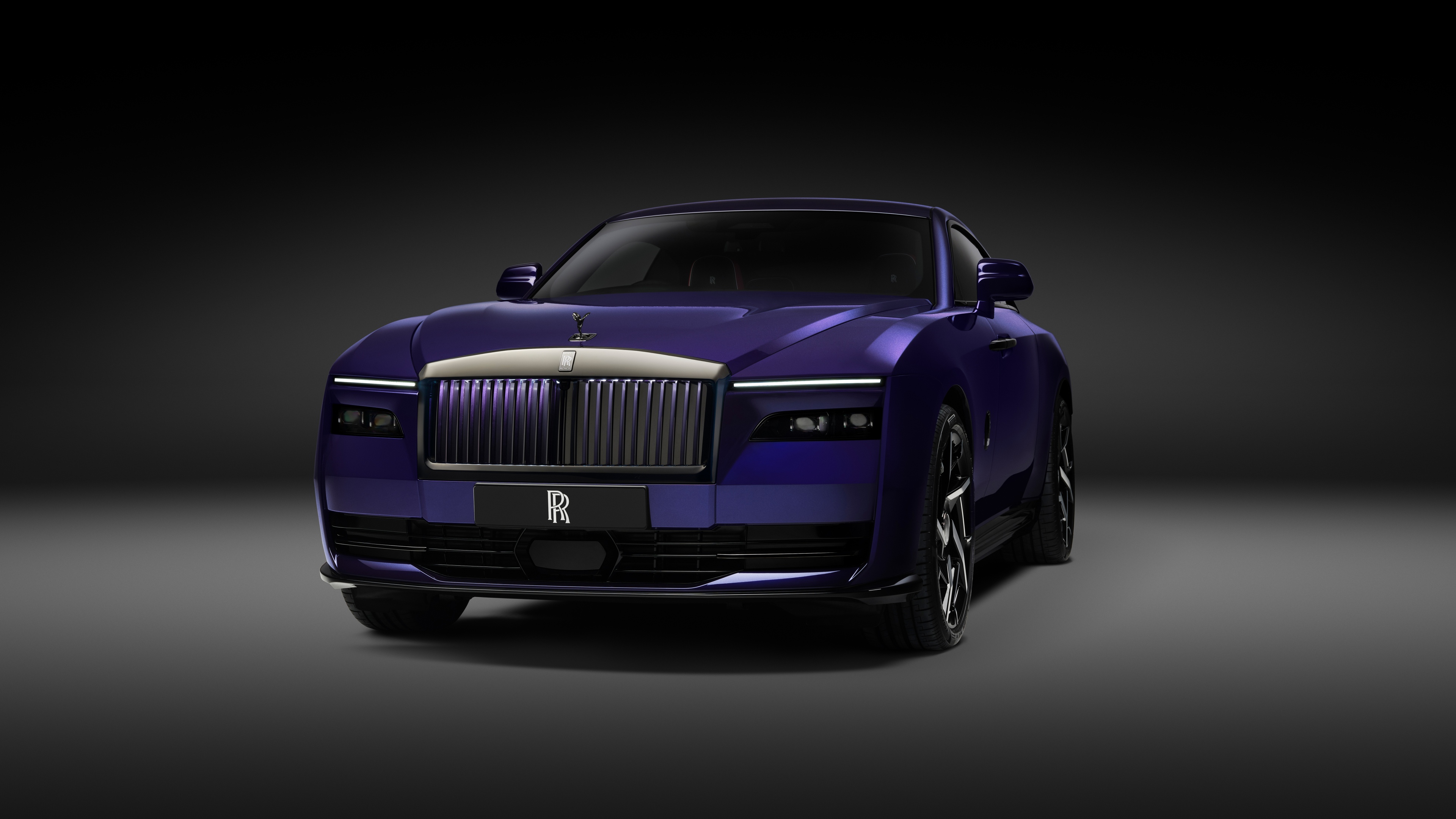 A sleek 2025 Rolls-Royce Black Badge Spectre luxury electric car presented against a dark, moody background in high definition.