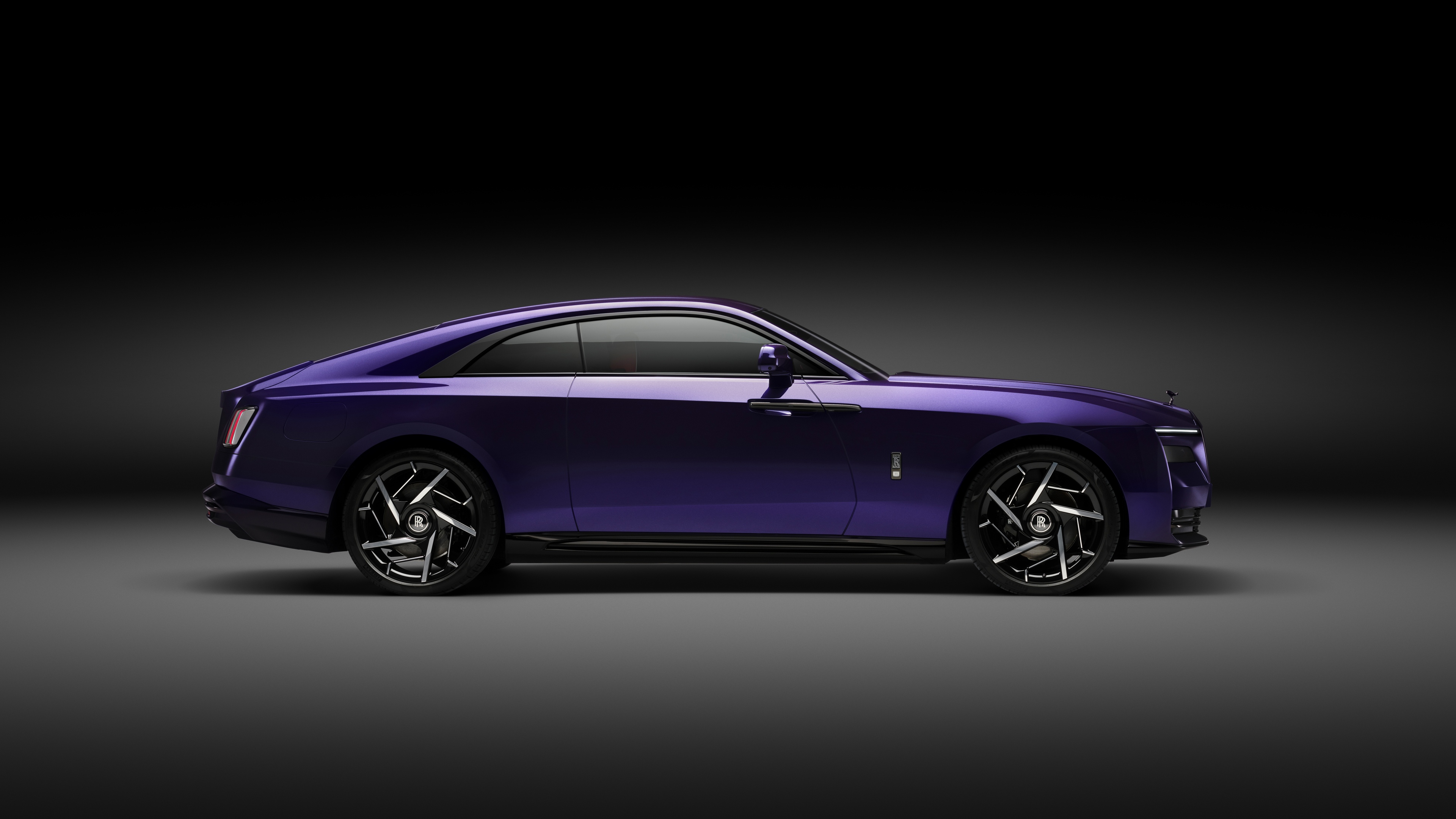 Cinematic shot of the 2025 Rolls-Royce Black Badge Spectre luxury electric vehicle in a dark, atmospheric setting.