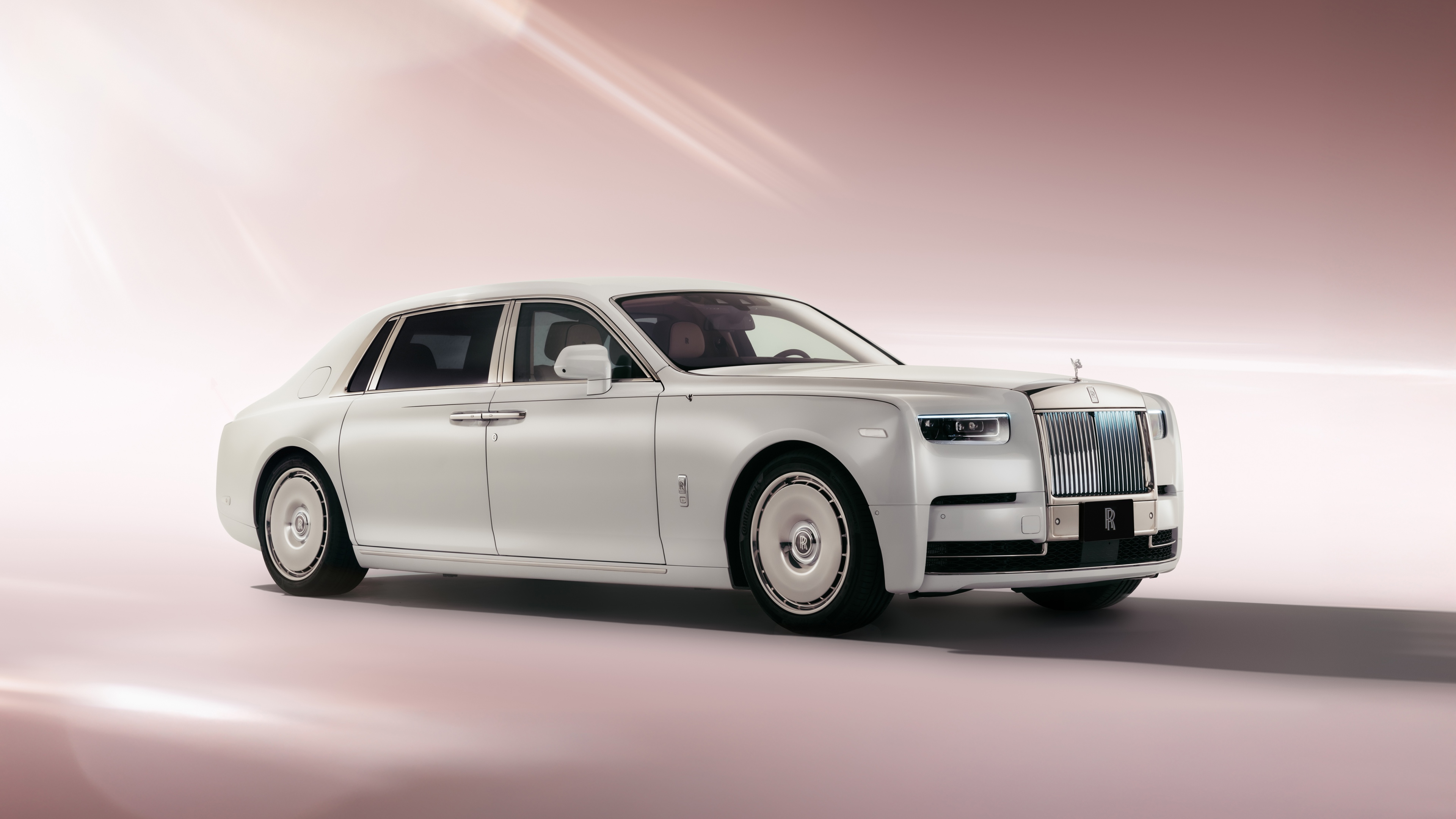 A 2025 Rolls-Royce Phantom EWB luxury sedan positioned against a soft, aesthetic pastel-colored background.