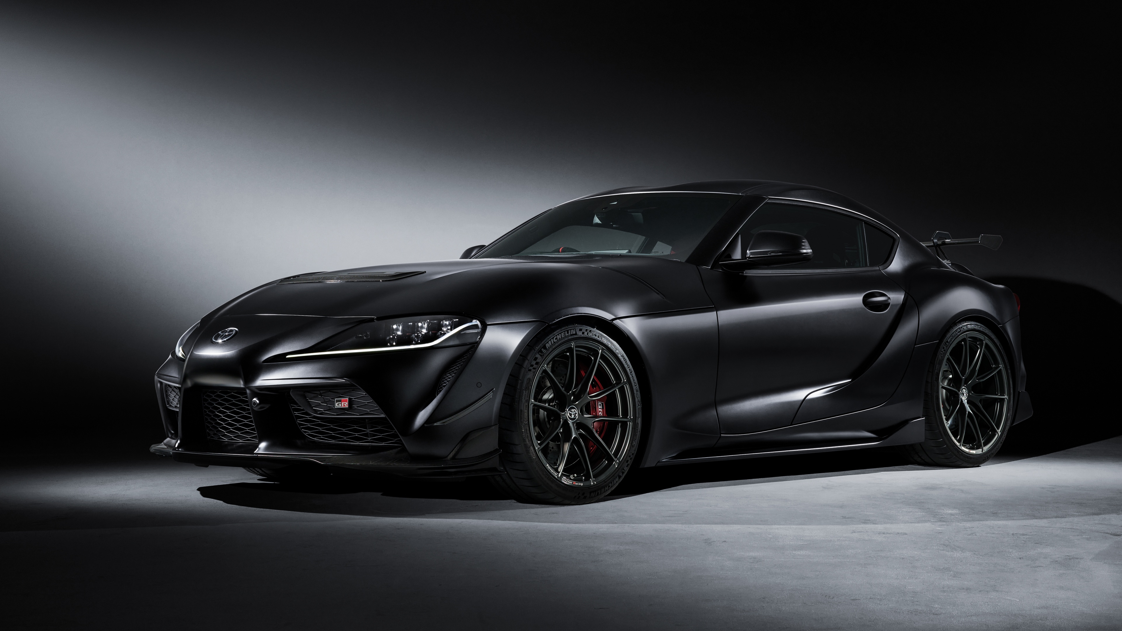 A sleek, glossy black 2025 Toyota GR Supra A90 positioned against a dark, moody background.