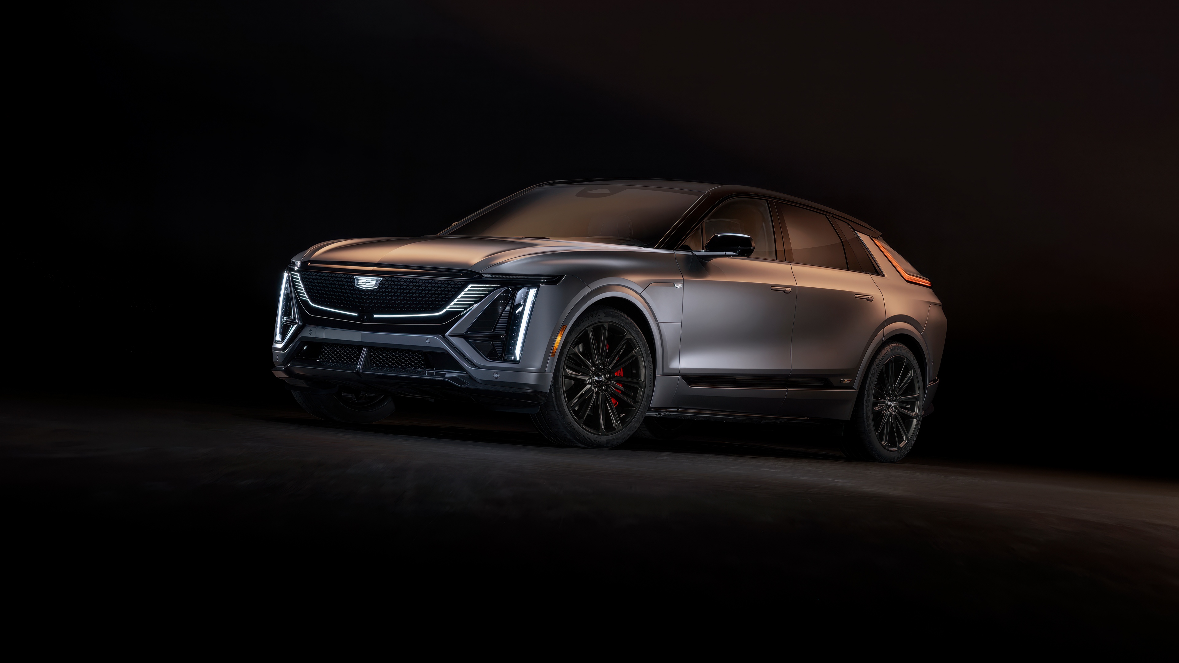 A sleek 2026 Cadillac Lyriq-V electric SUV presented in a high-contrast, dark setting.