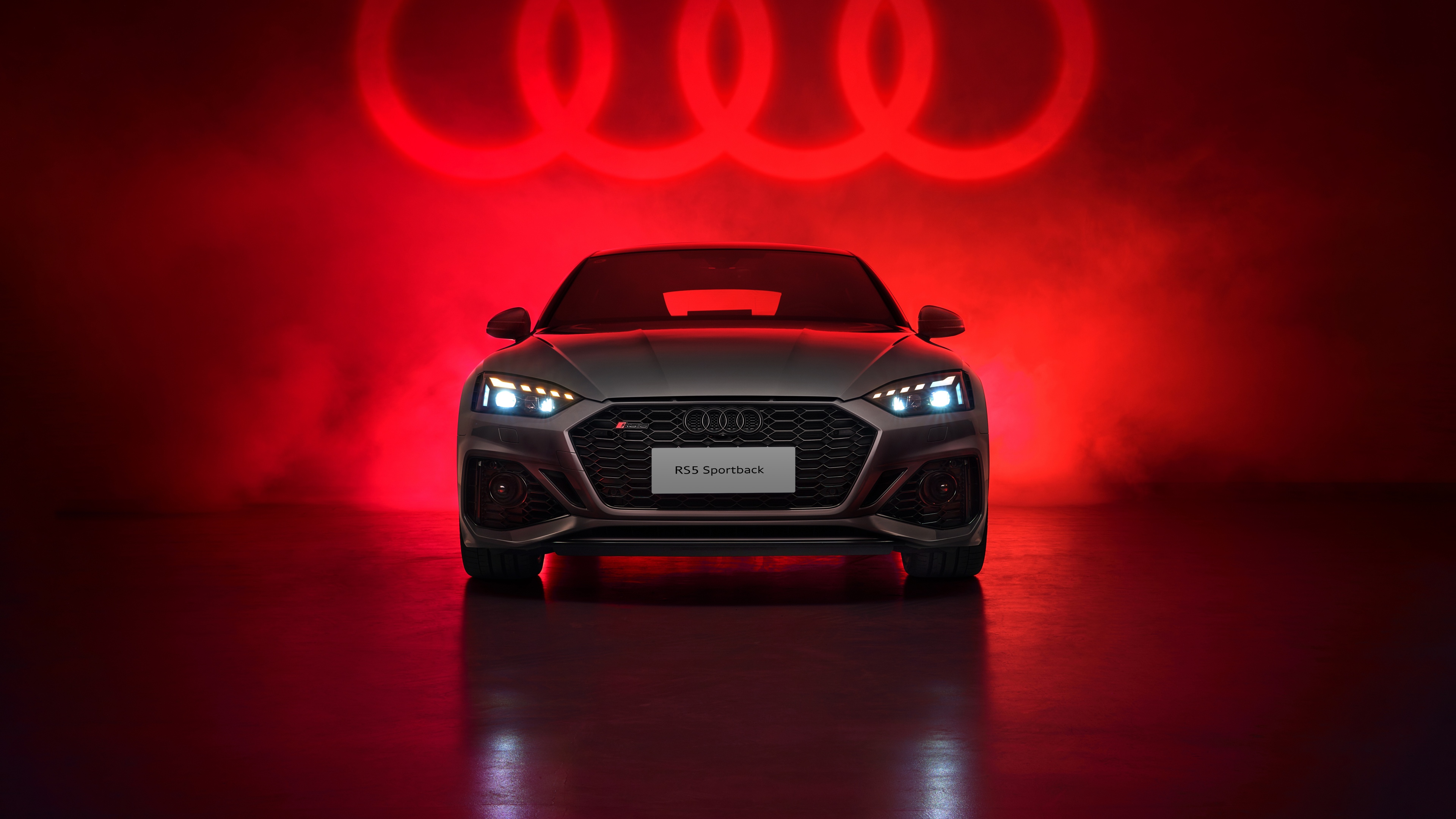 A high-detail shot of an Audi RS 5 Sportback against a vivid red aesthetic background.