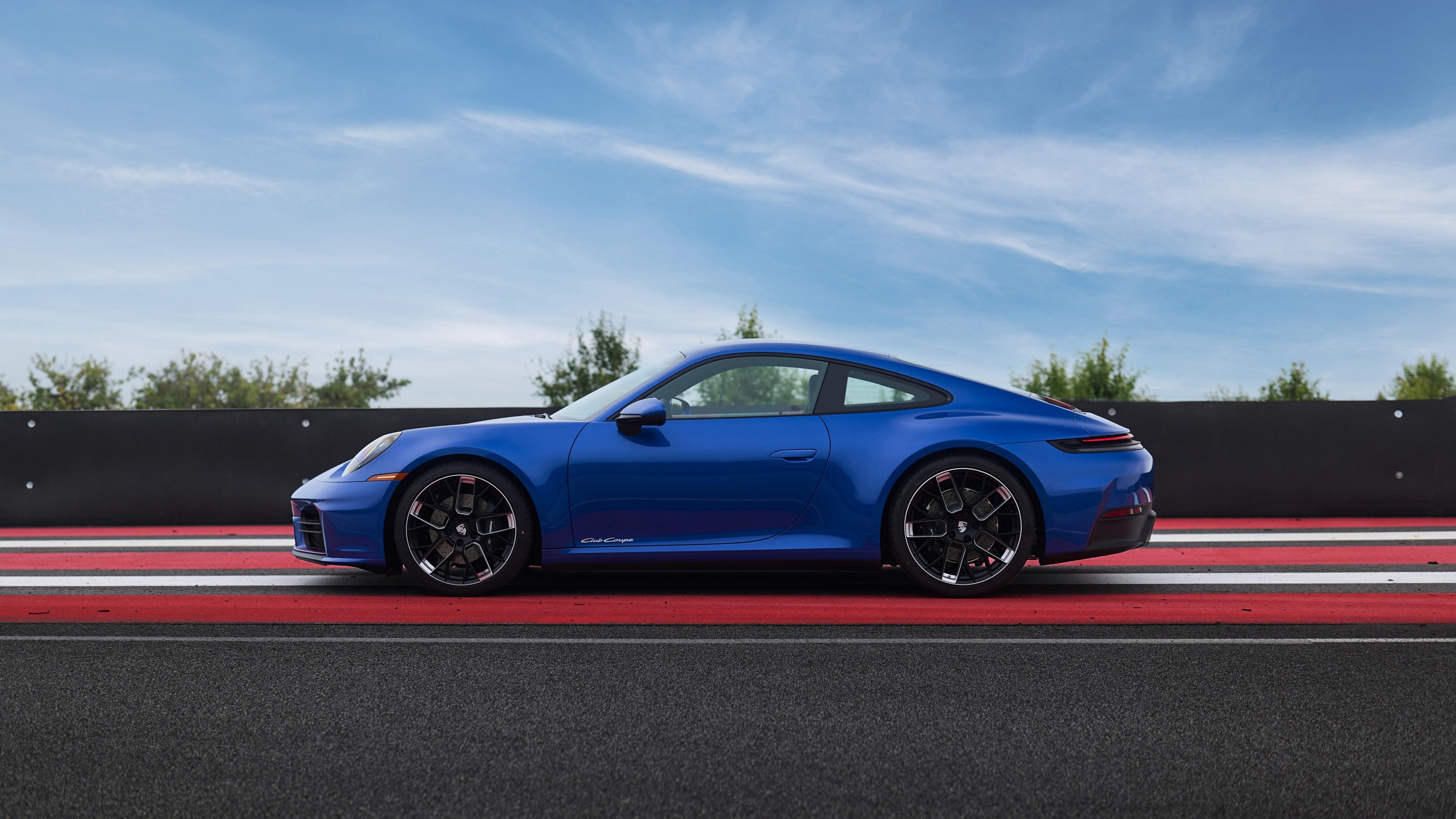 A sleek blue Porsche 911 Carrera sports car driving on a racetrack.