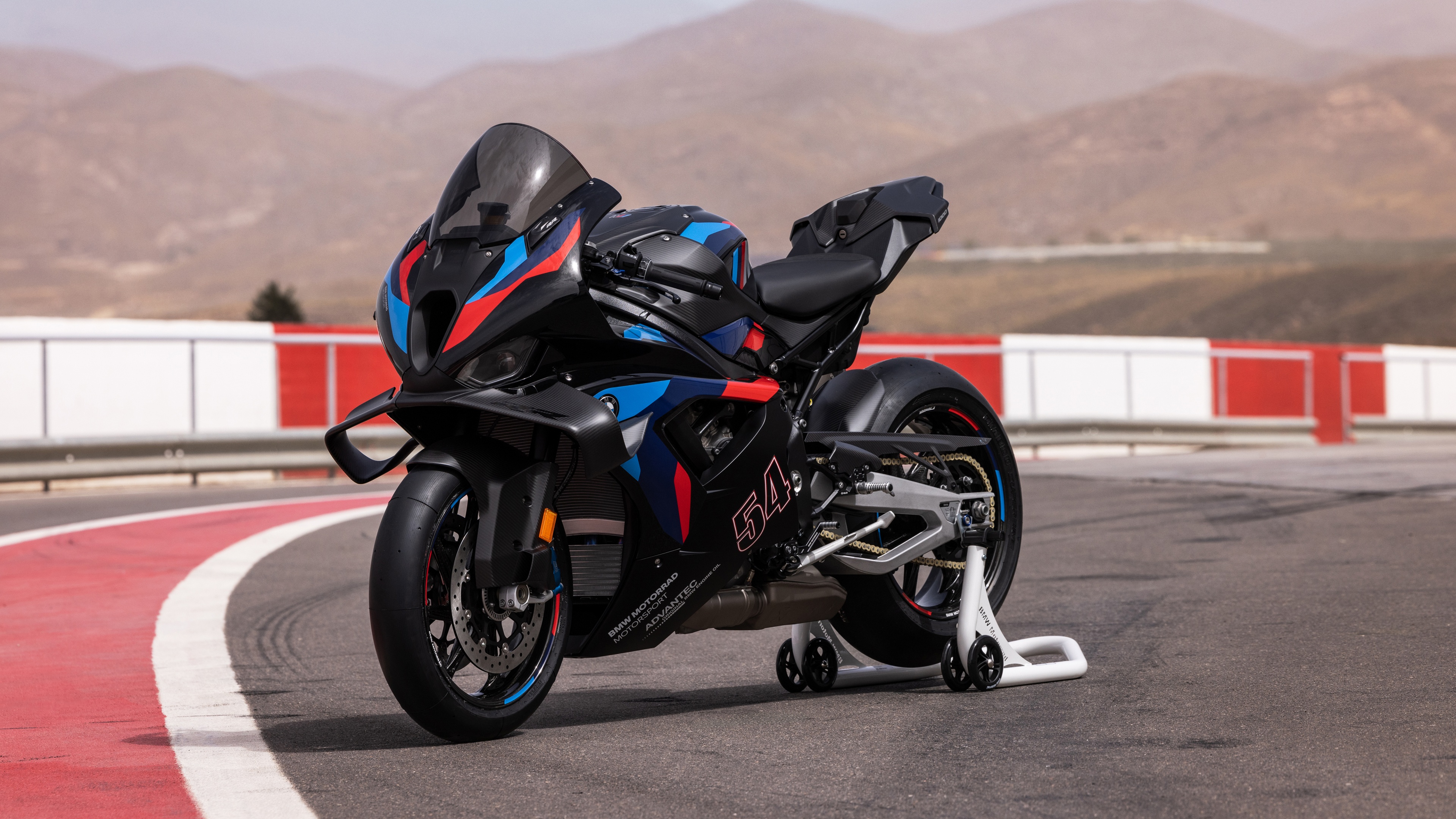 A sleek BMW M 1000 RR M Competition motorcycle positioned on a professional race track circuit.