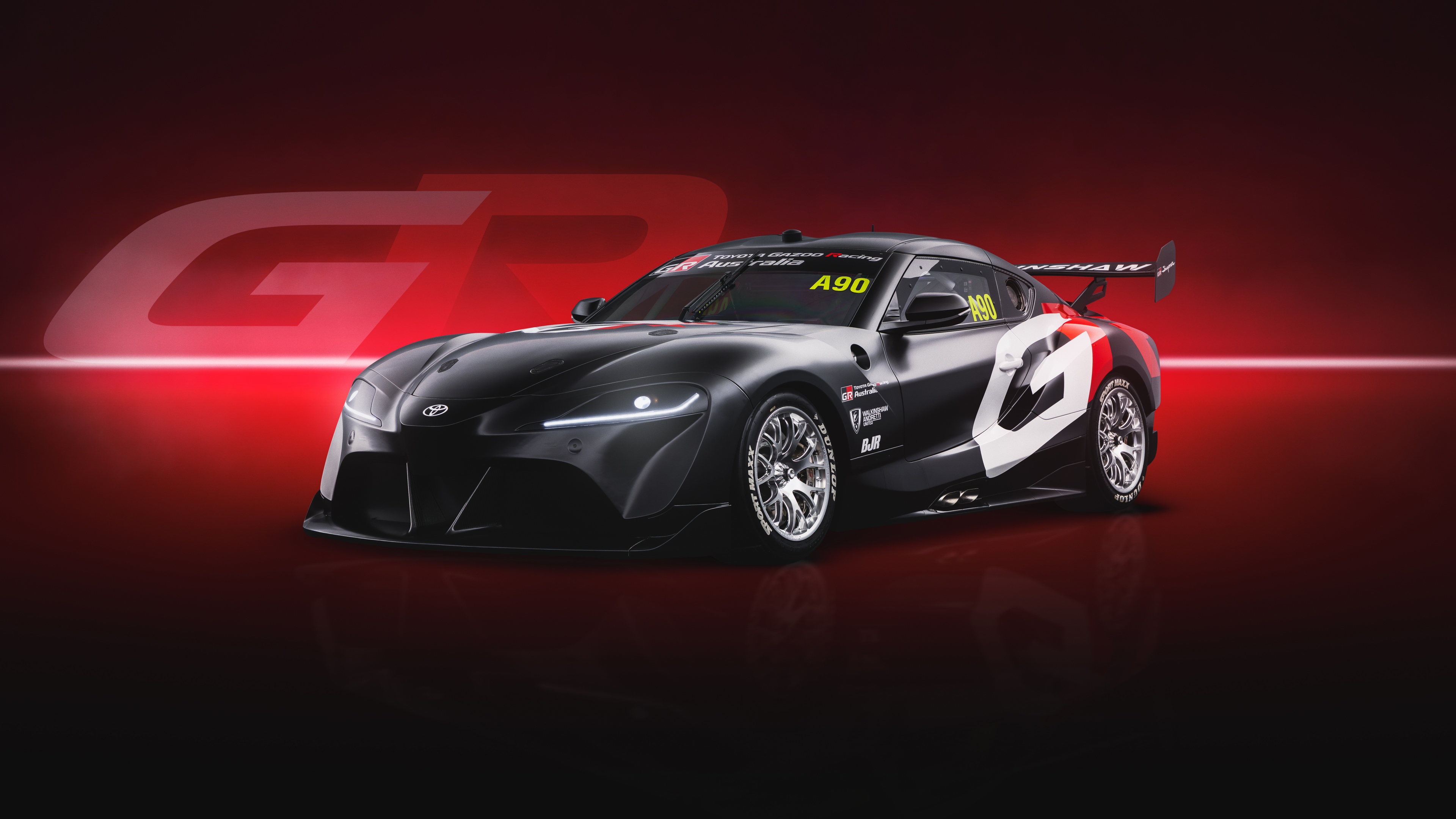 A high-resolution, cinematic view of a Toyota GR Supra supercar set against a dark red, monochromatic background.