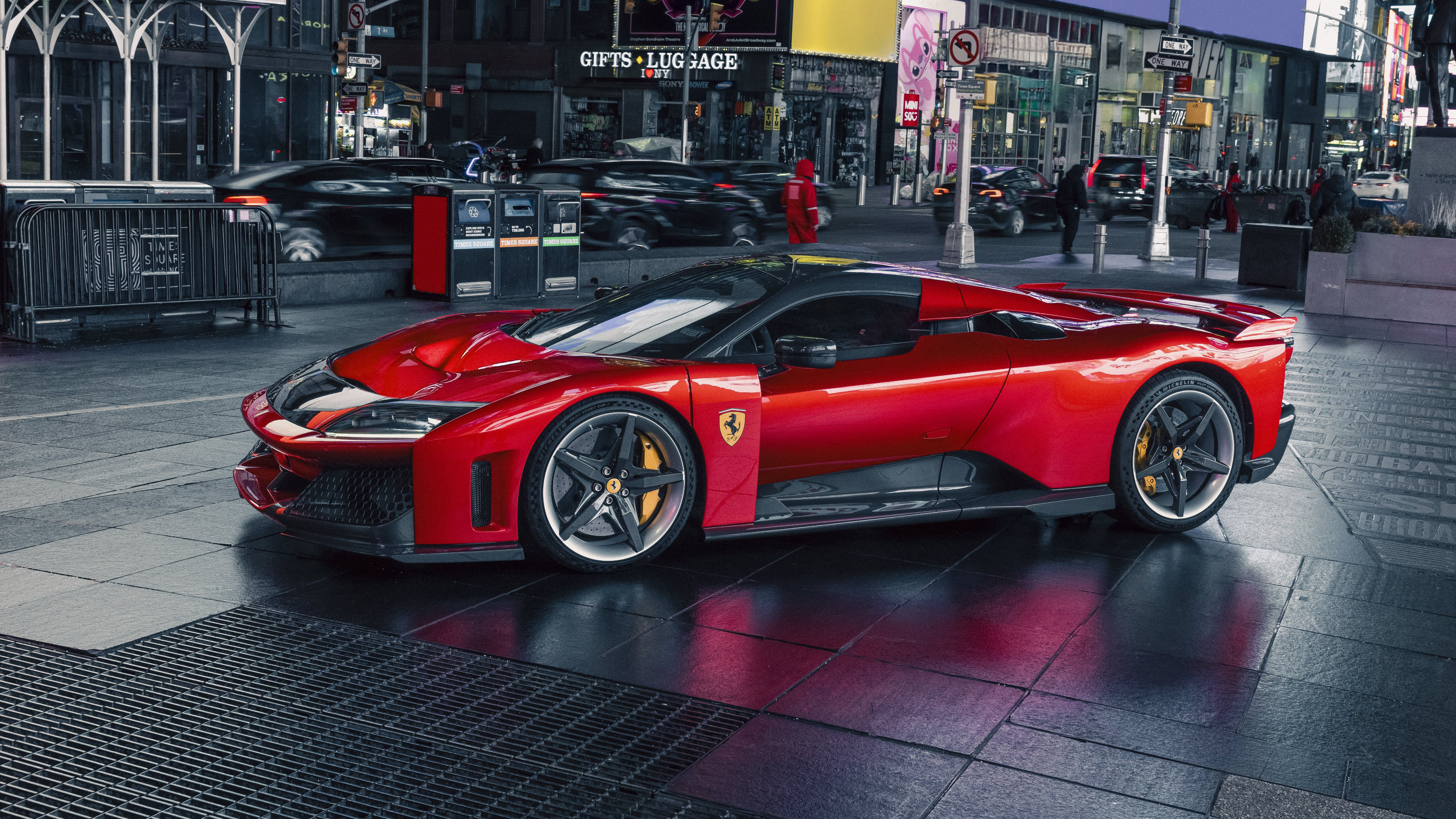 A bright red Ferrari F80 supercar driving through a modern city street with urban lights reflecting on its surface.