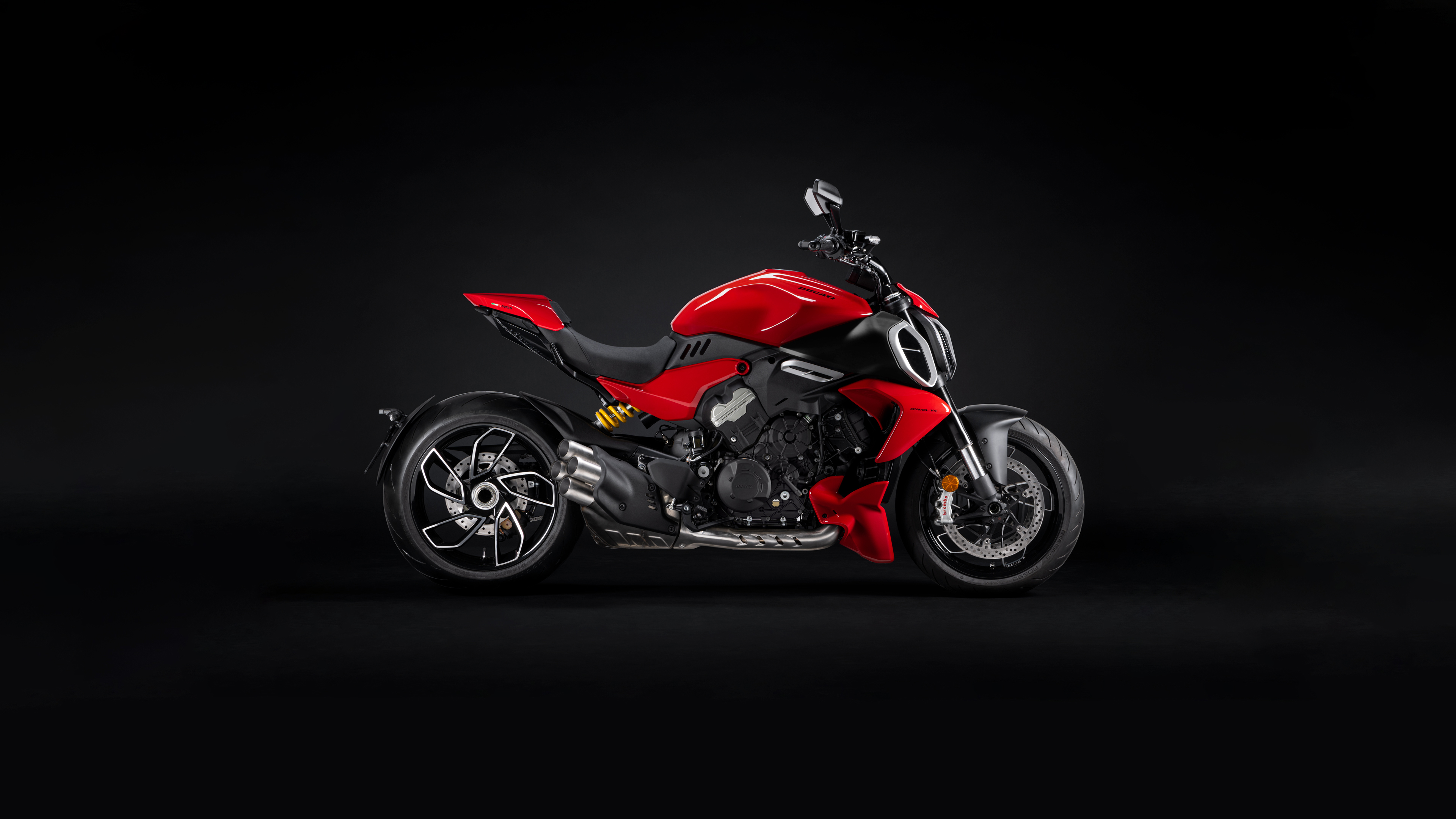 A vibrant red Ducati Diavel V4 motorcycle positioned against a dark, atmospheric background.