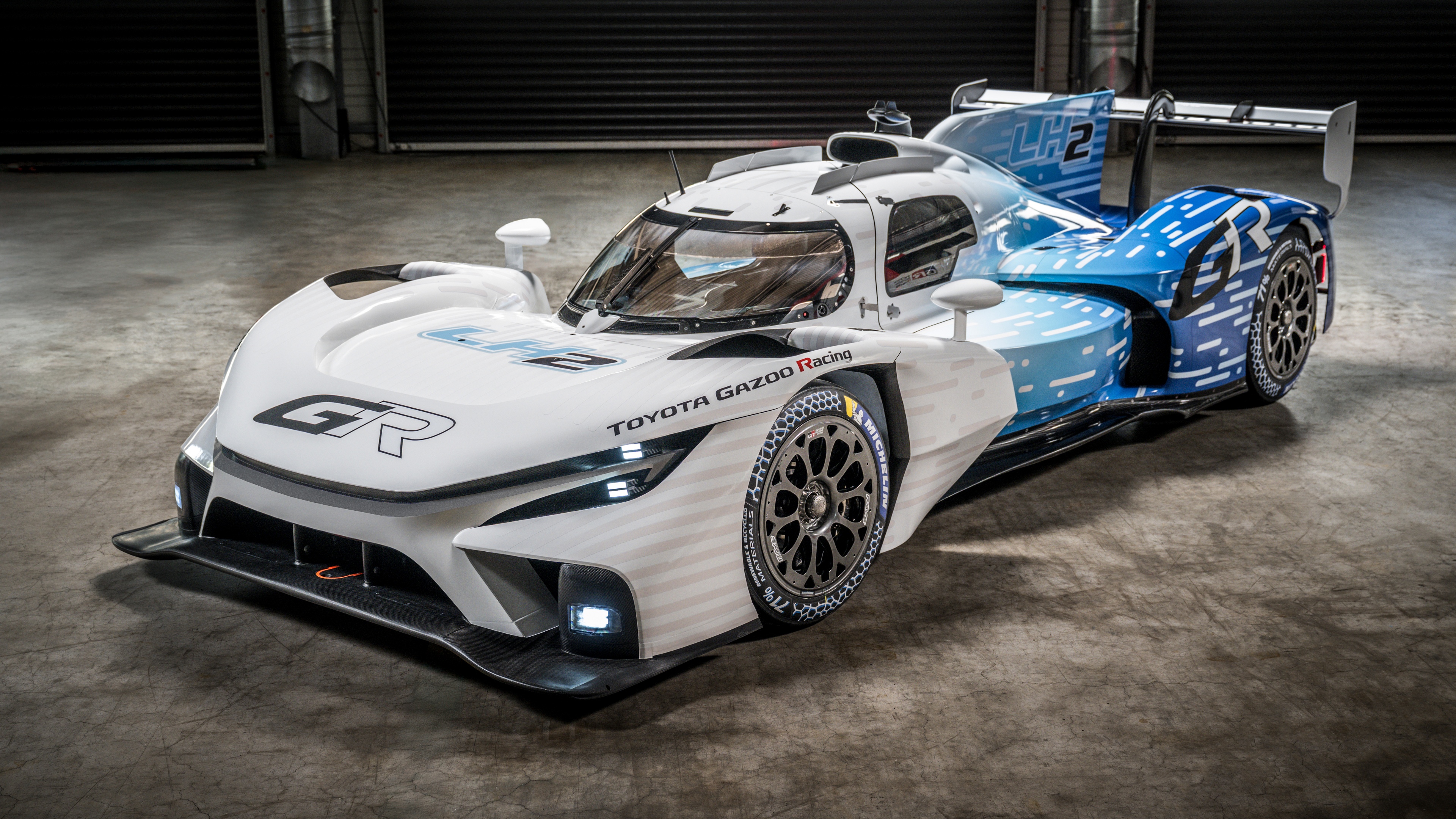 Ultra-high-definition futuristic racing cars with aerodynamic bodies speeding on a modern racetrack.