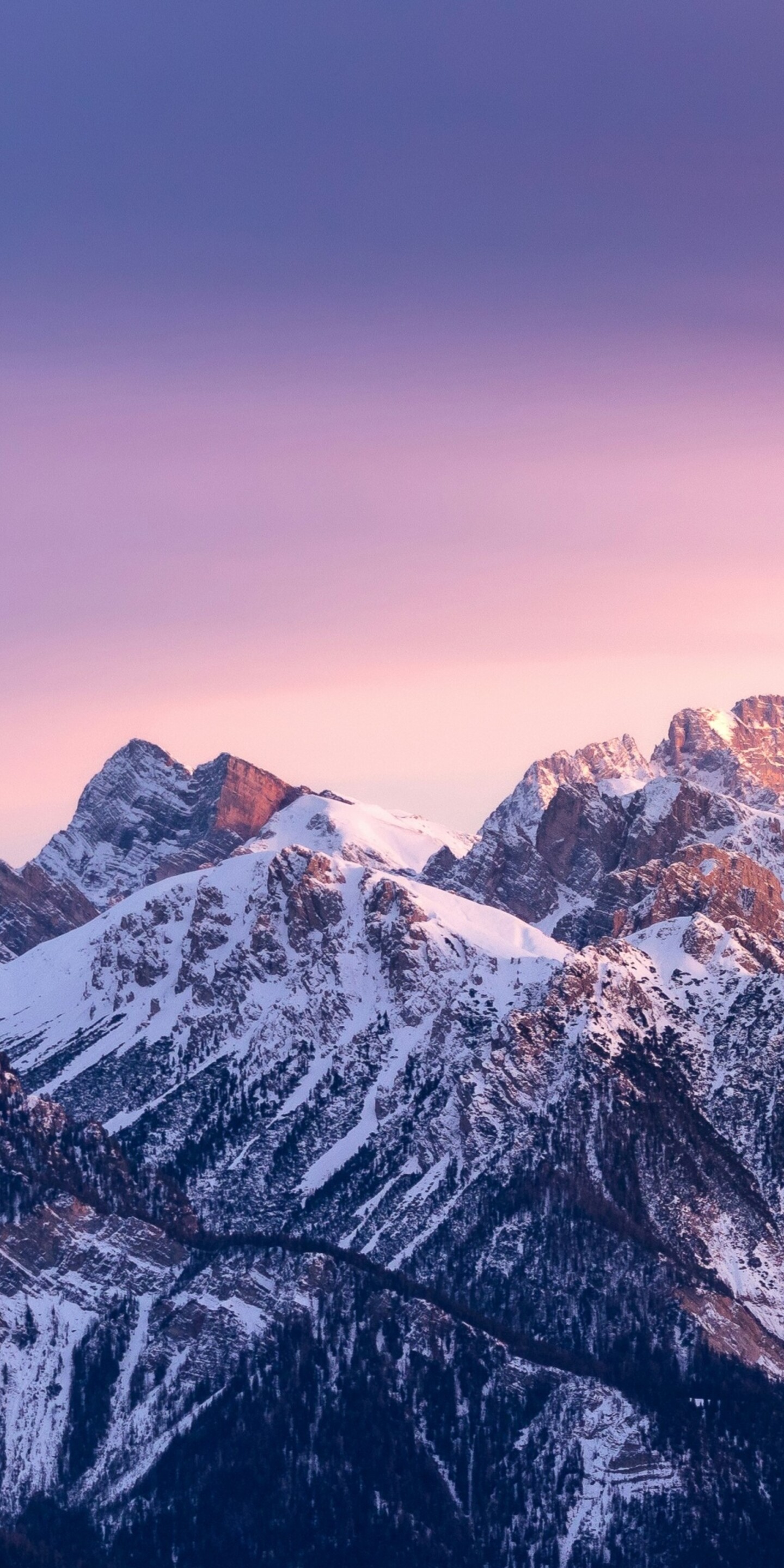 Sunset over snow-capped mountain peaks with a colorful gradient sky