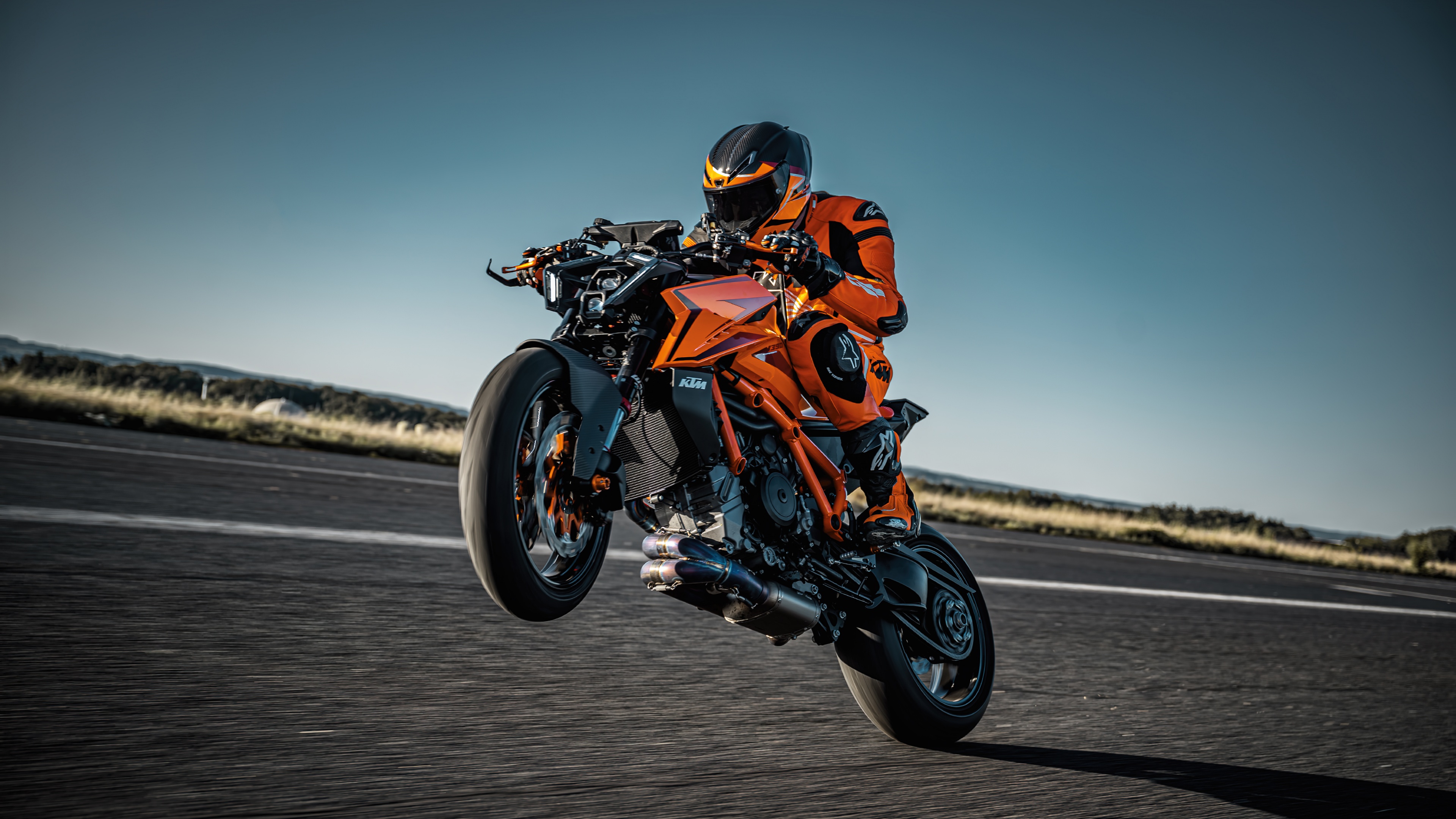 A biker riding a 2024 KTM 1390 Super Duke R through a turn on a professional racing circuit.