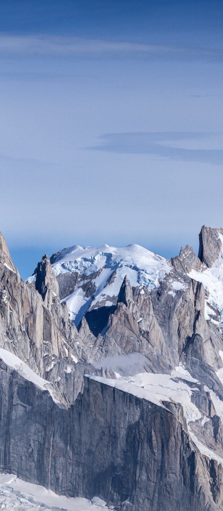 Snow-covered peaks of Cerro Torre and Fitz Roy mountains in Patagonia under a bright blue sky