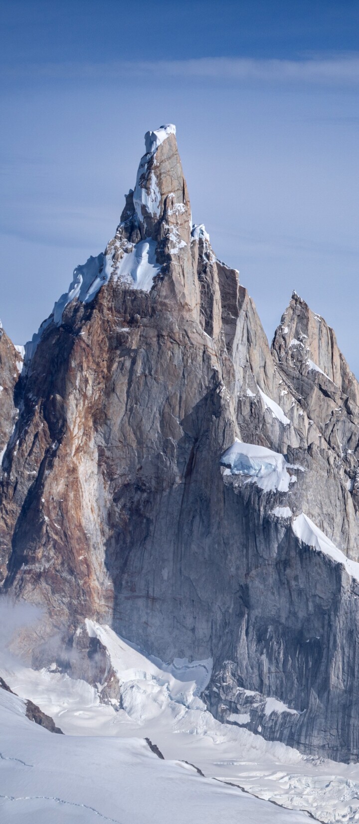 Snow-covered peaks of Cerro Torre and Fitz Roy in the Patagonian Andes under a clear blue sky.