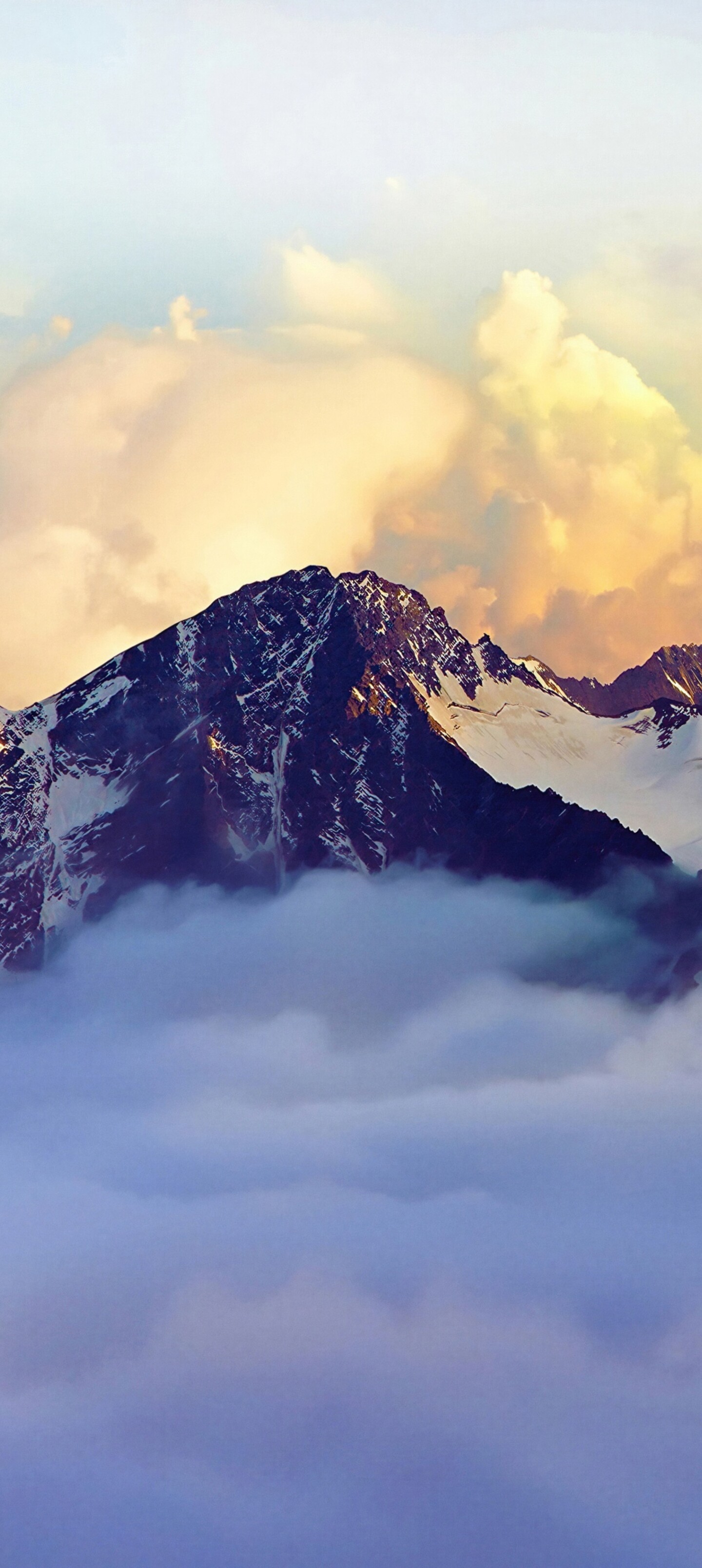 A panoramic view of snow-covered mountain peaks in the Alps partially shrouded in fog and clouds.