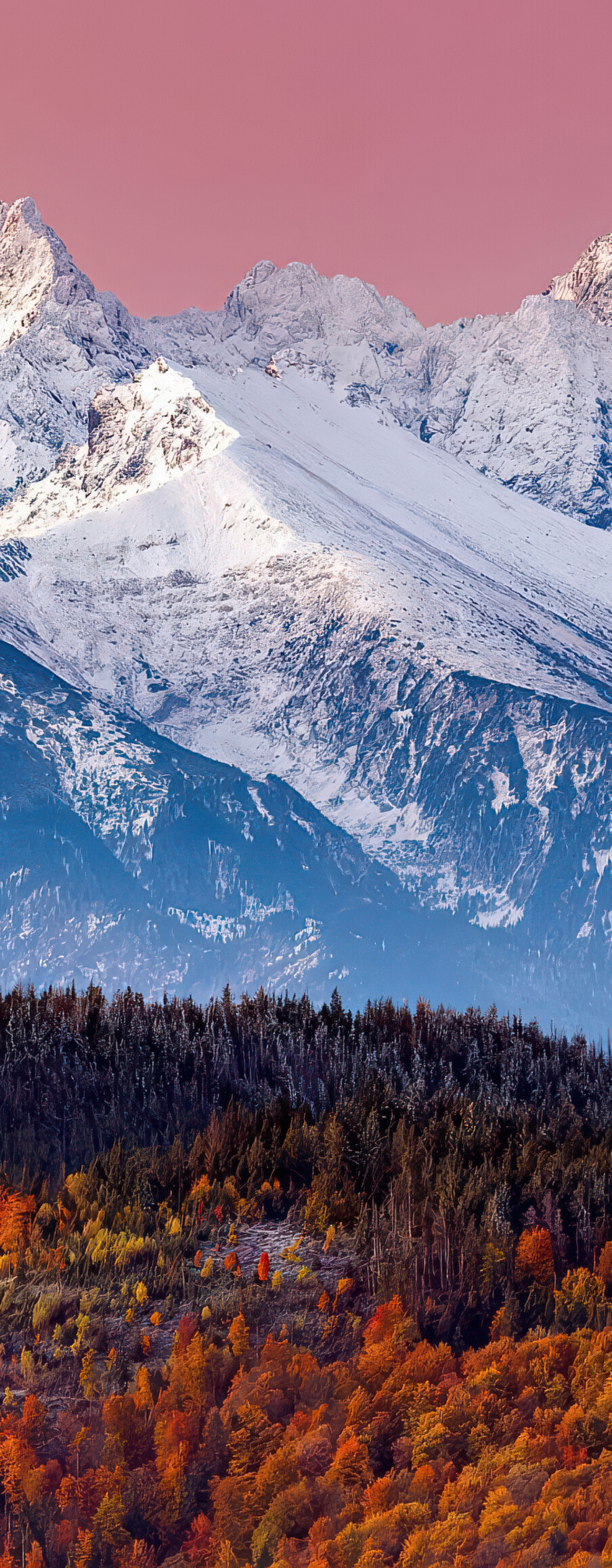 A scenic view of the snow-capped Tatra Mountains with a pink twilight sky and golden autumn trees.