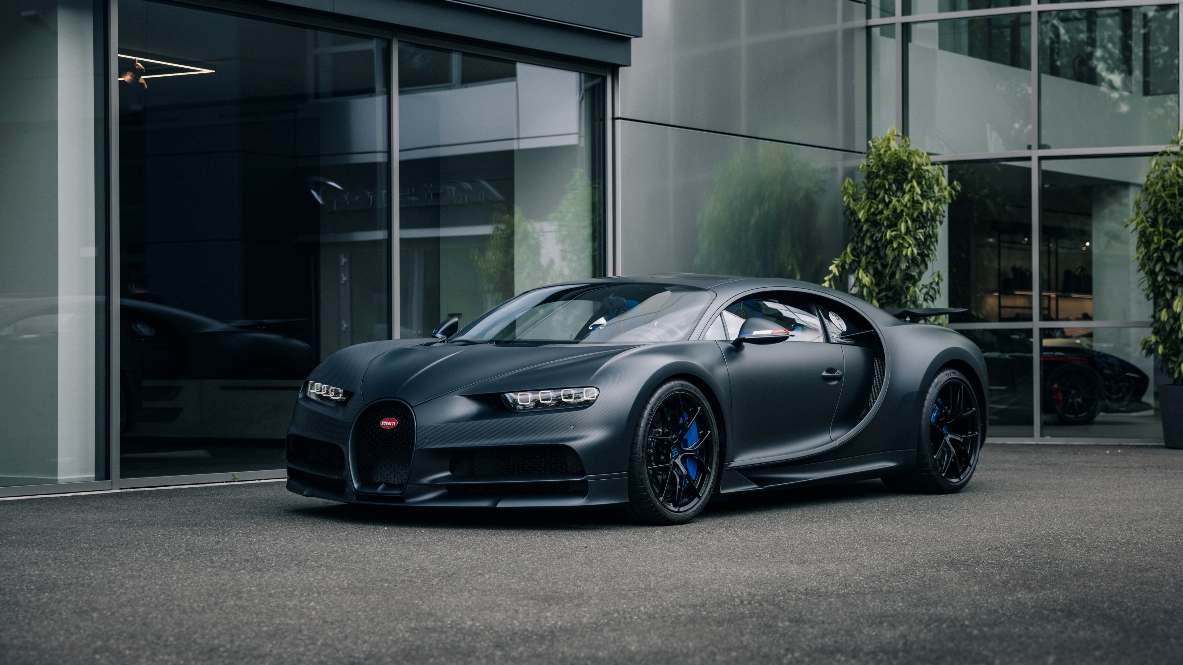 A matte black Bugatti Chiron Sport parked on a city street under urban lighting.
