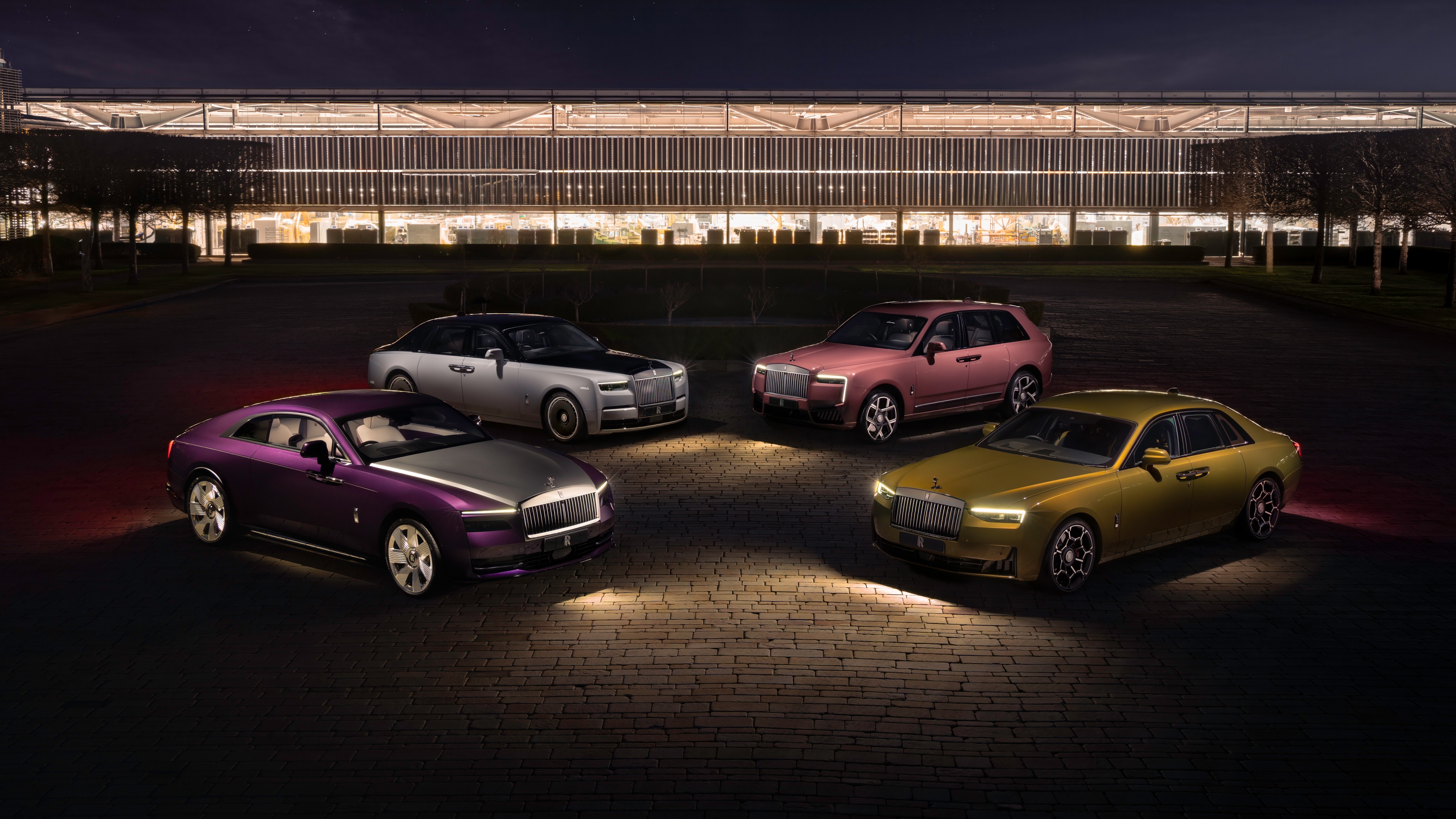 A lineup of luxury Rolls-Royce cars, including the Cullinan, Phantom, and Spectre, illuminated in a dark, cinematic night setting.