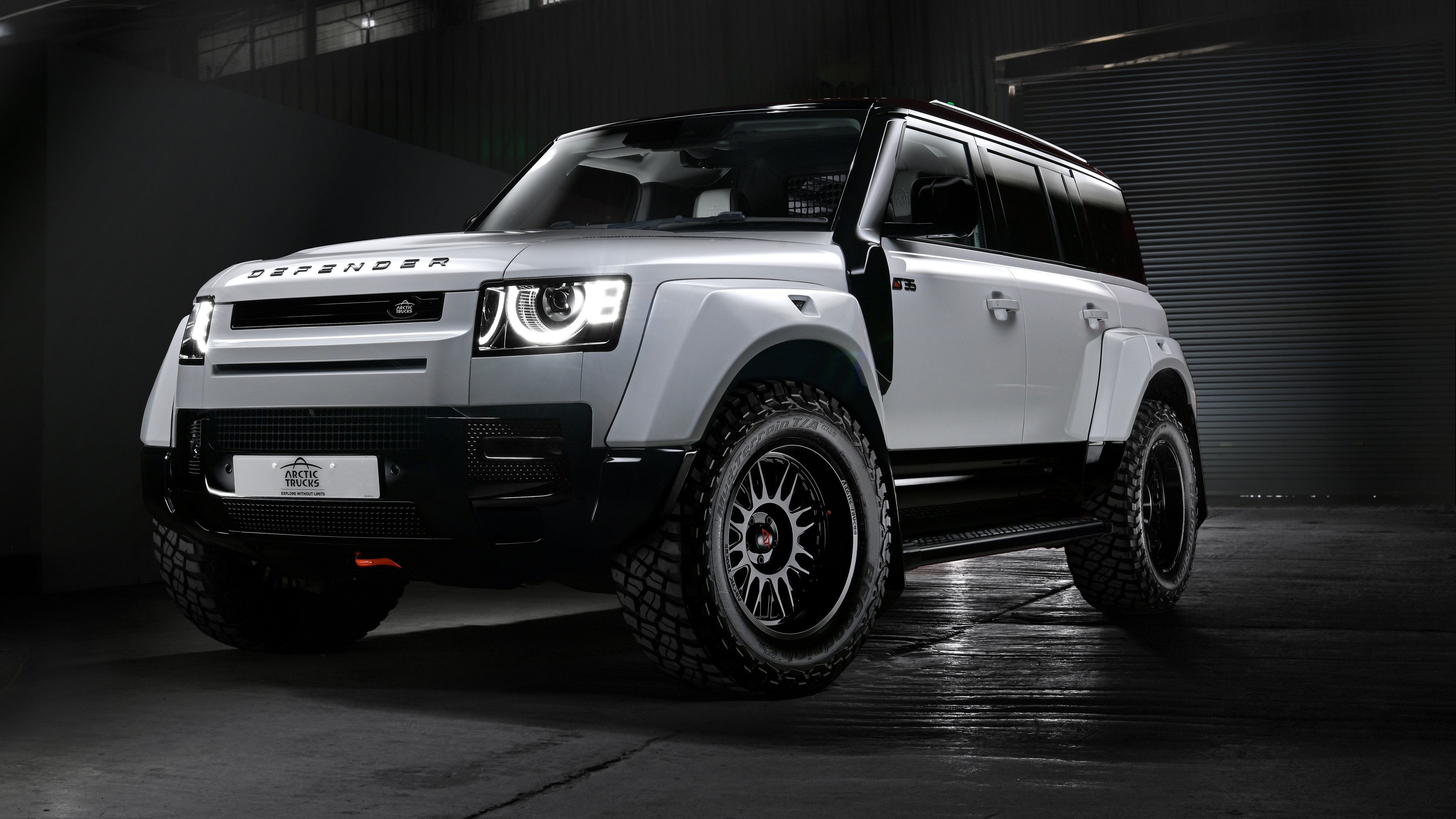 A high-resolution, dark-themed shot of a modern Land Rover Defender 110 featuring a sleek, cinematic aesthetic and moody lighting.