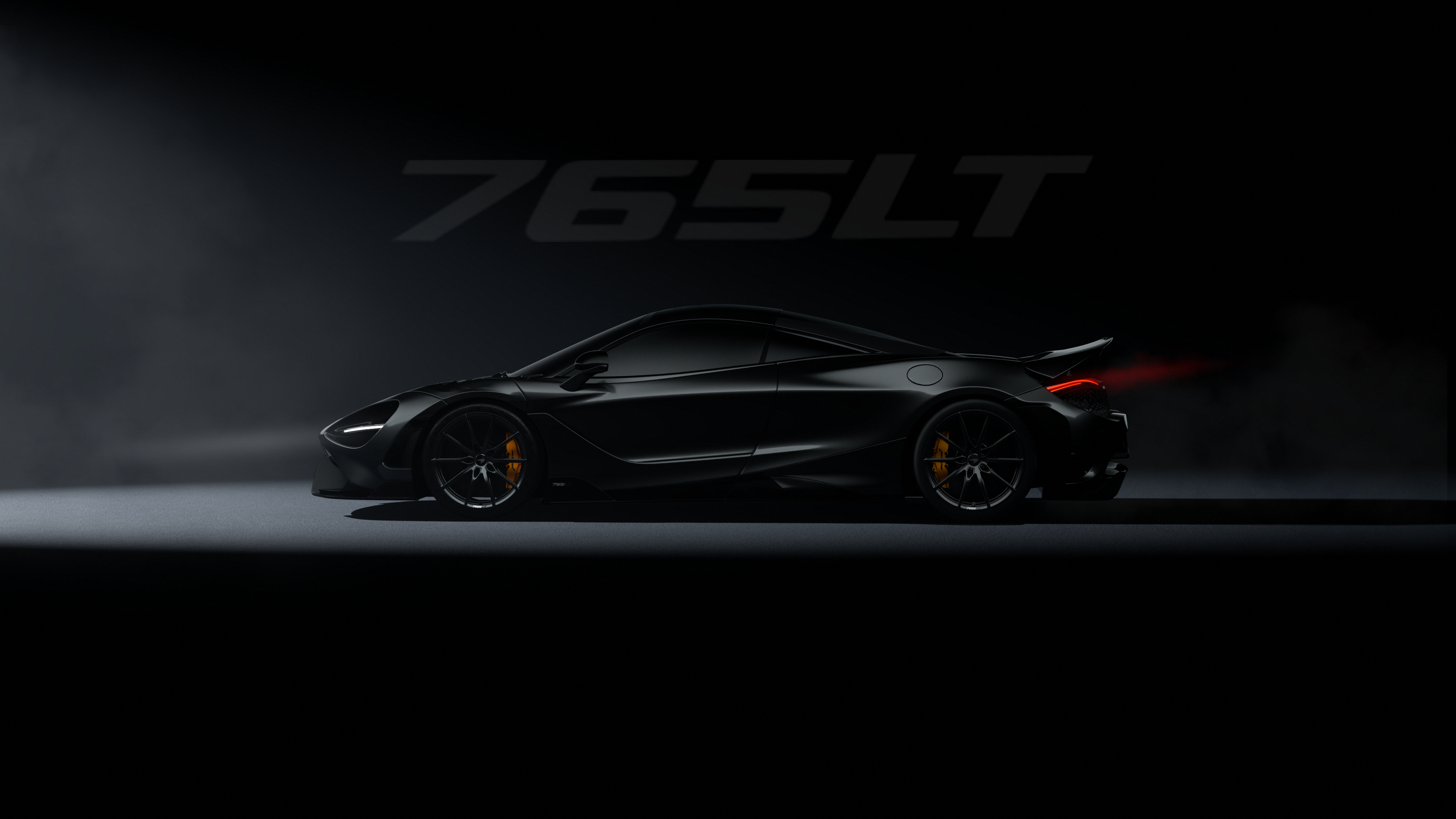 A black McLaren 765LT supercar in a dark, cinematic setting with moody lighting.
