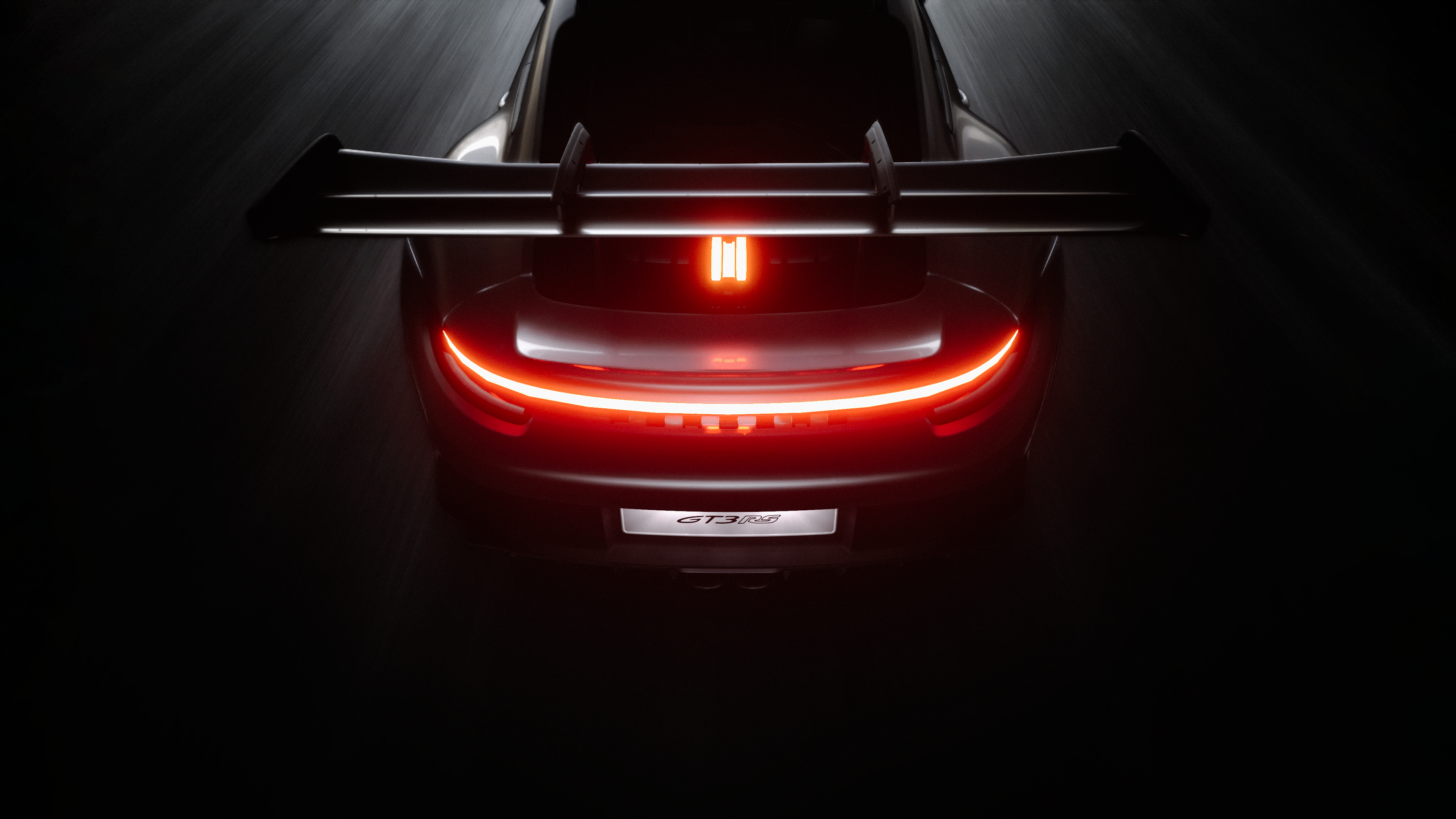 Rear view of a Porsche 911 GT3 RS featuring a dark aesthetic with glowing light accents against a black background.