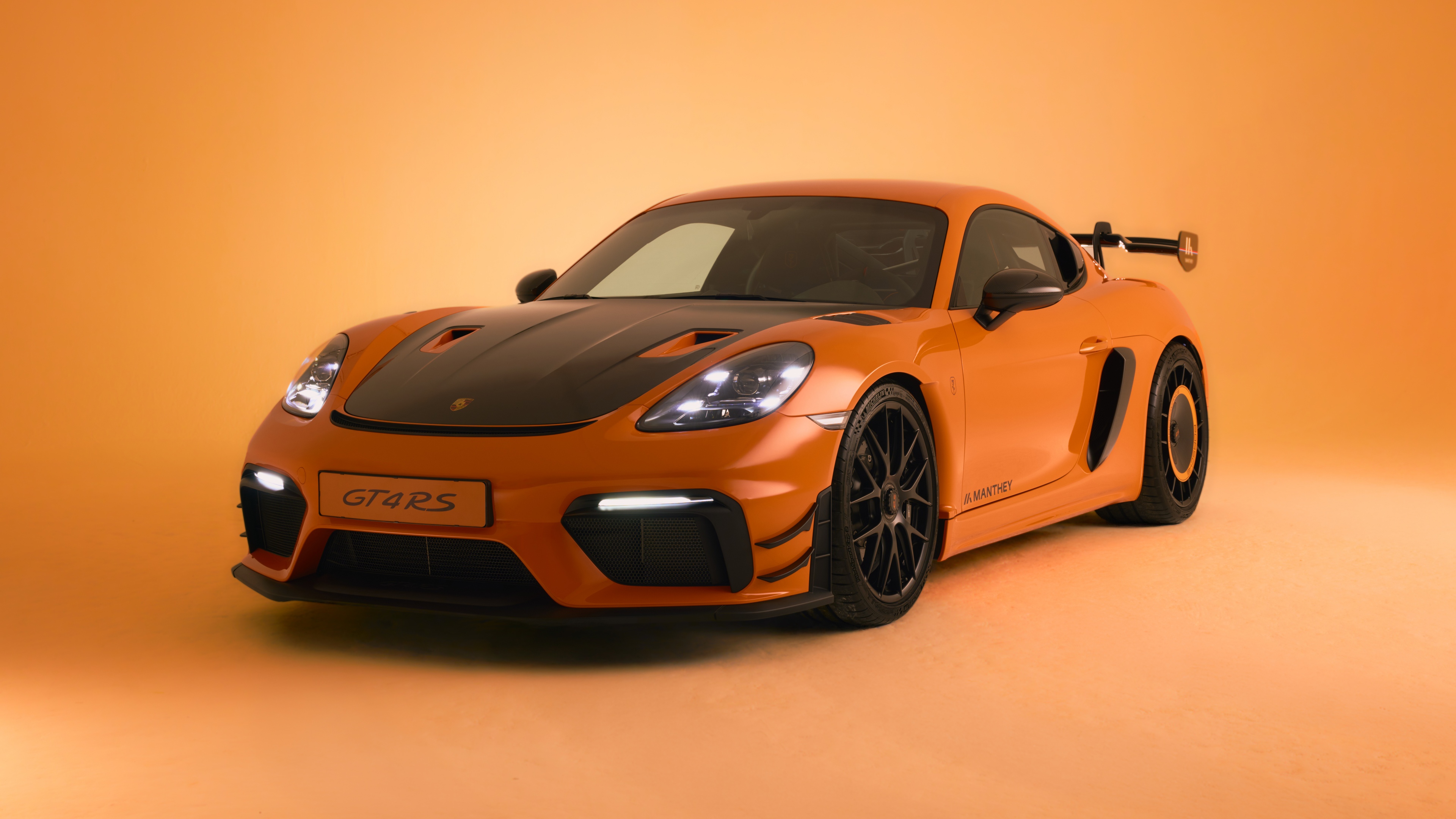 A sleek Porsche 718 Cayman GT4 RS presented in a striking orange color scheme.