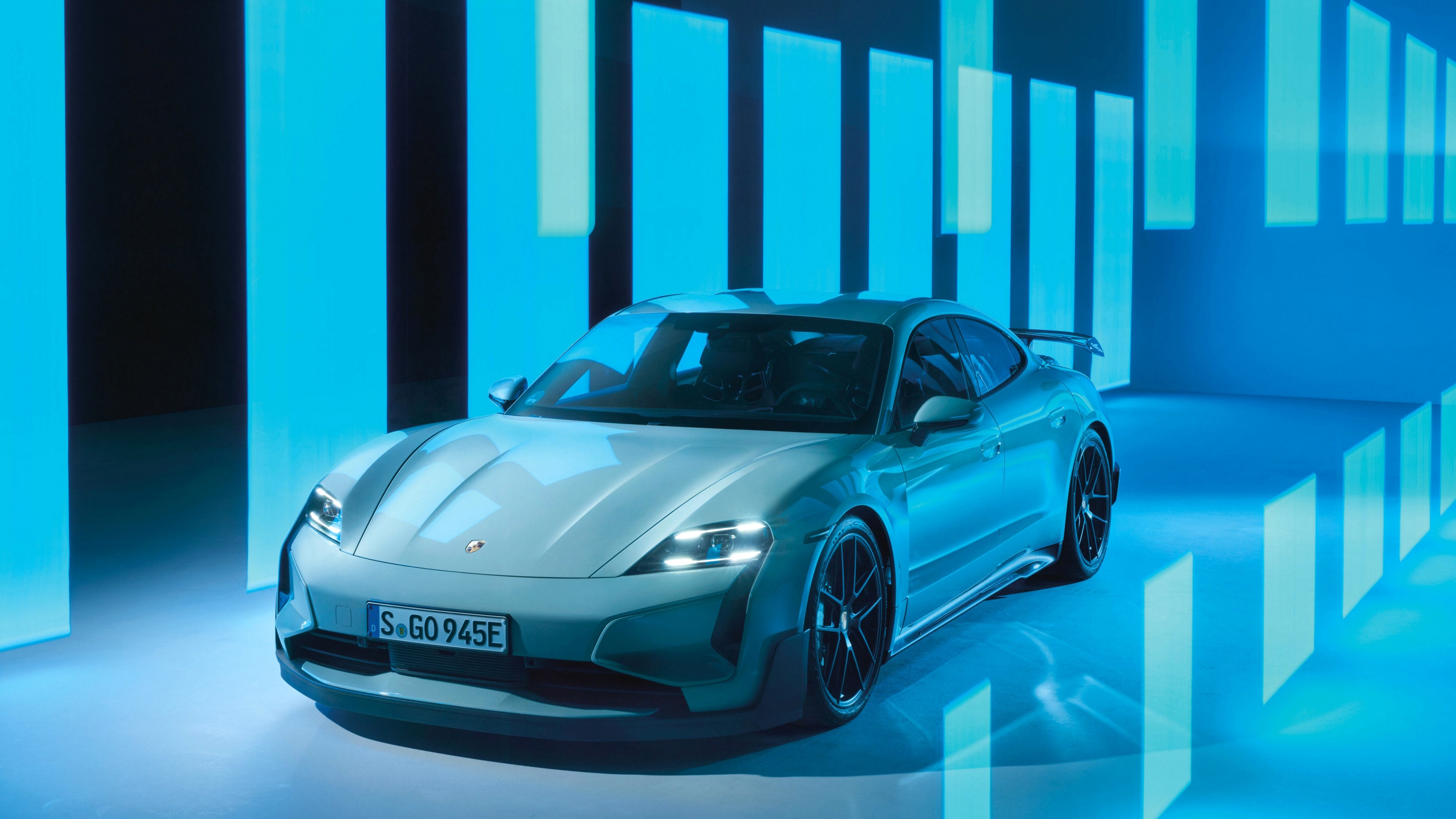 Porsche Taycan Turbo GT with Weissach package displayed against a solid cyan background.