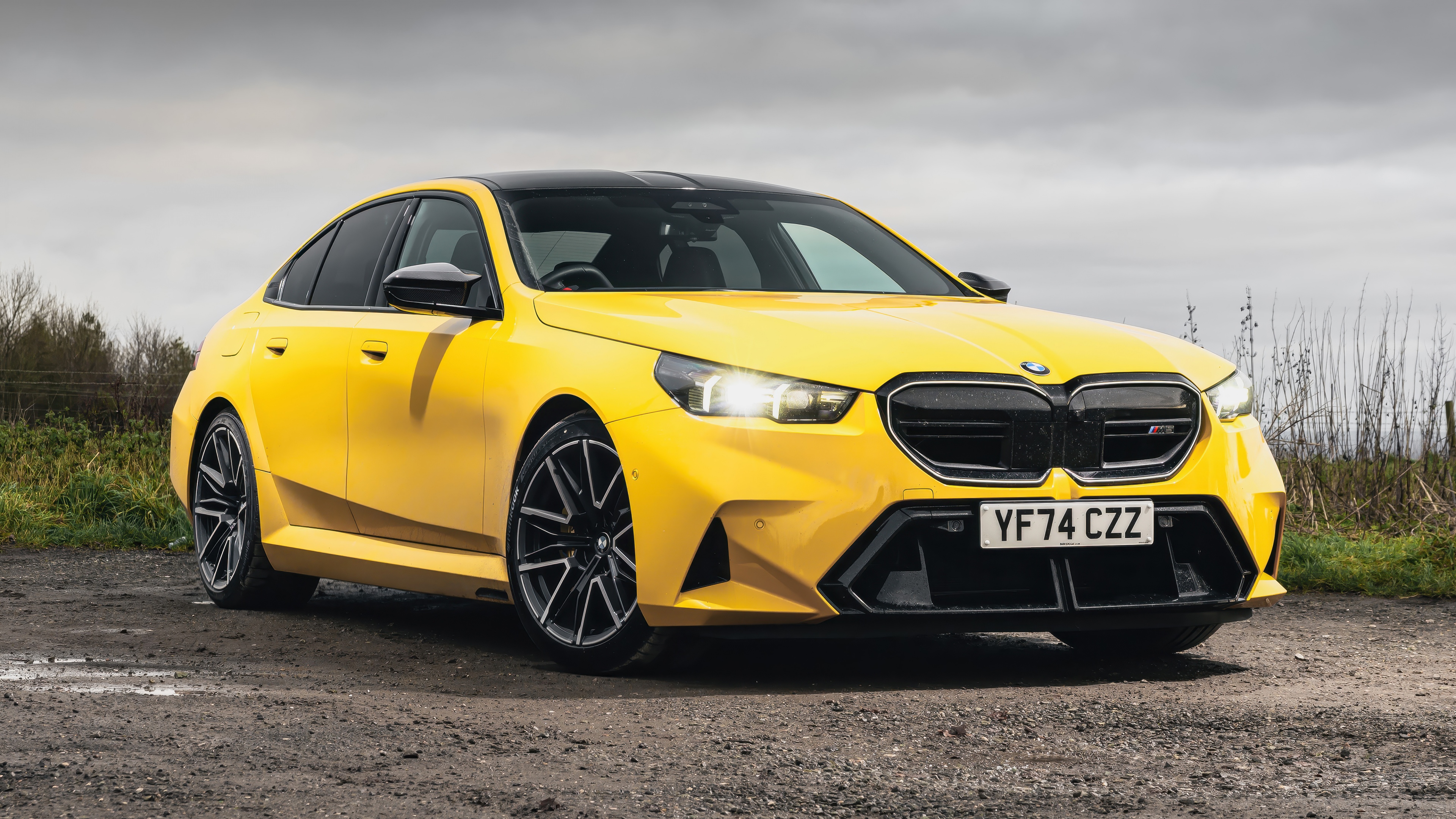 A high-resolution, detailed shot of a polished yellow BMW M5 luxury sedan showcasing its sleek aerodynamic lines.