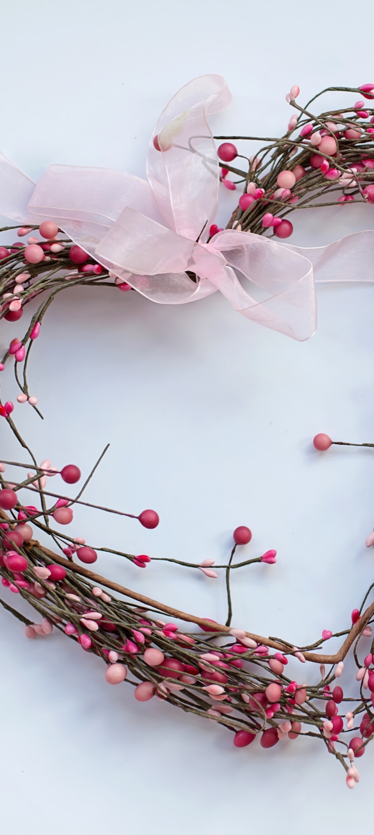 A heart-shaped wreath featuring pink spring flowers and green leaves on a white background.