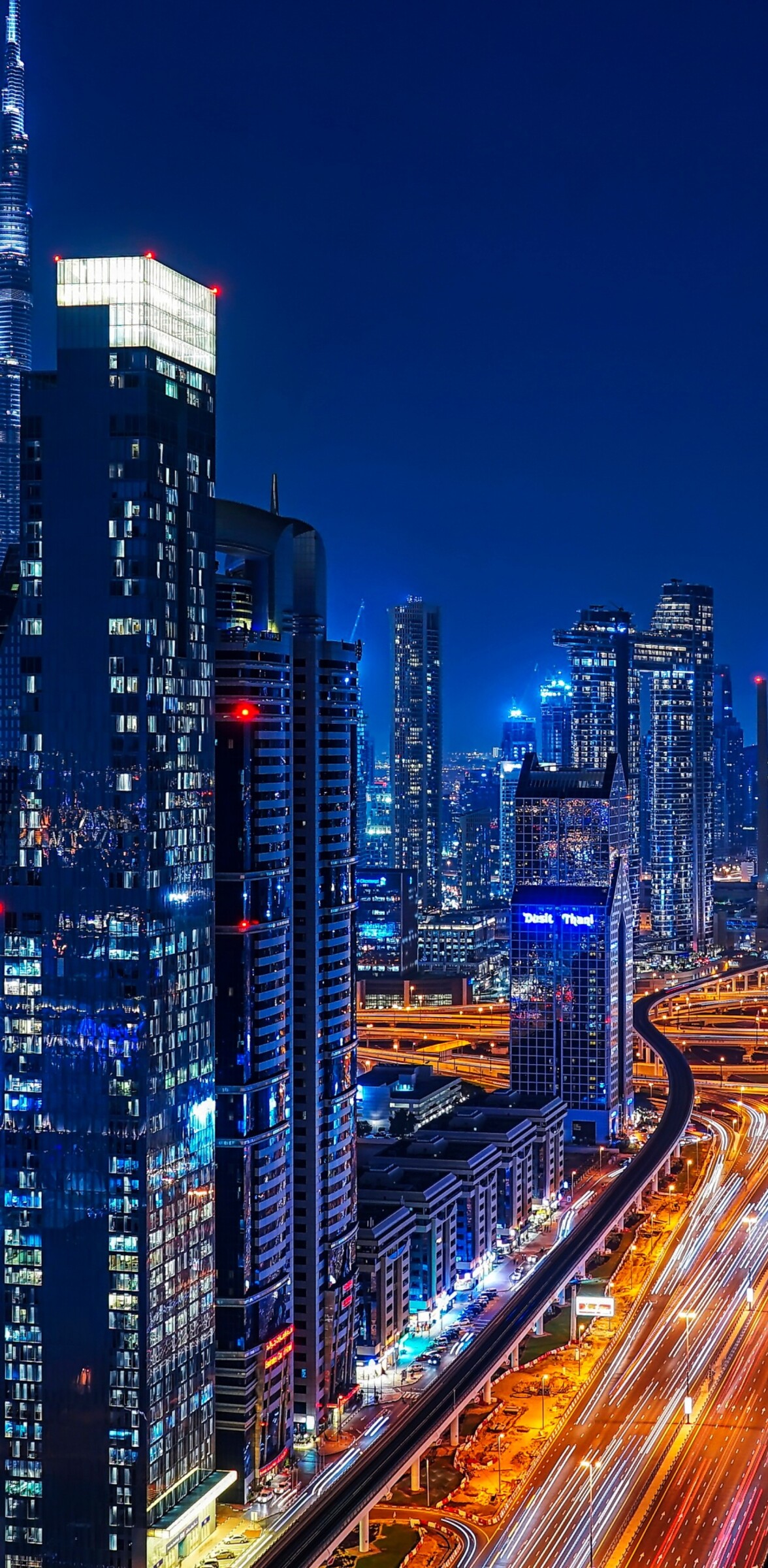 A stunning night view of Dubai's illuminated skyscrapers and vibrant city lights along Sheikh Zayed Road.
